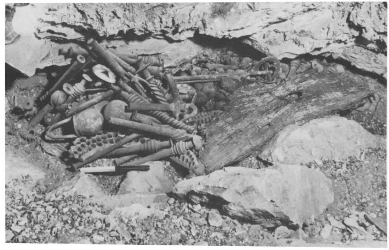 Fig. 21. The me in from Nahal Mishmar as found in the cave, covered with a mat and hidden in a niche.  The cave relevant to our subject was excavated by P. Bar-Adon** and labelled by him “The Cave of the Treasure.” The cave is situated in the canyon of Nahal Mishmar, about six miles south of Ein Gedi. The cave opens onto the vertical cliff, about 150 feet below the cliff top with an abyss of nearly 800 feet below it. Access to the place was made possible during the excavations with the aid of ropes and rope-ladders. The cave was inhabited twice, first by the Ghassulians and later in 135 A.D., when Jewish rebels of the Second Revolt against the Romans took refuge there. 