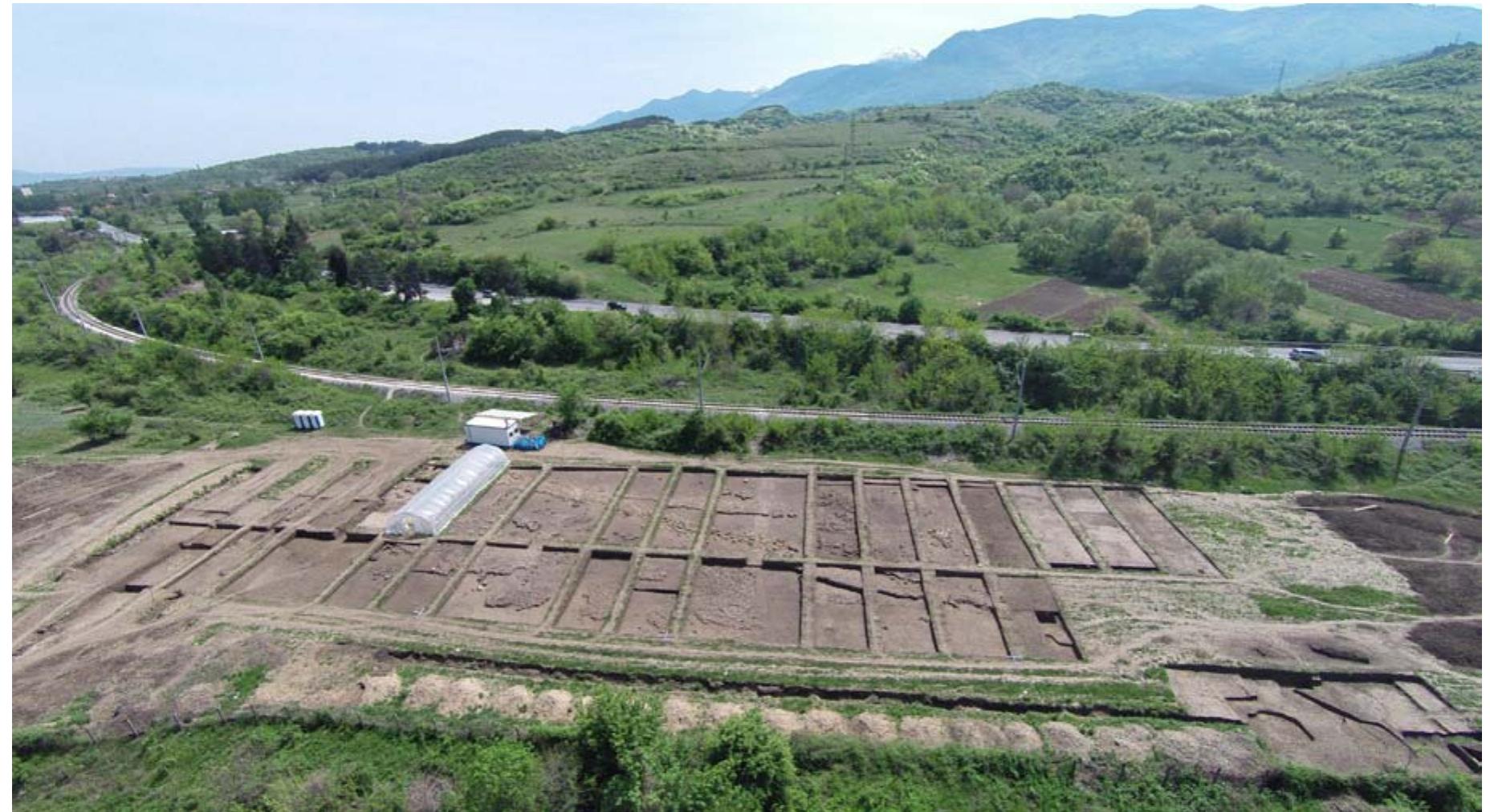 Fig. 7. The site during the rescue excavations. In the background are the Rila Mountain footslopes, whence the debris flow originated (aerial photo I. Vajsov) Oop. 7. Bo3sdyuina cHuMKA Ha ObeKMA NO 6peme Ha cnacumeanume paskonku. B dareuunama — ckAoHObeme Ha Puaa, omKbvOeMO Ca CBAUMAHUAMA Ha 3emHa Maca (cHum«Ka VI. Baticos) 