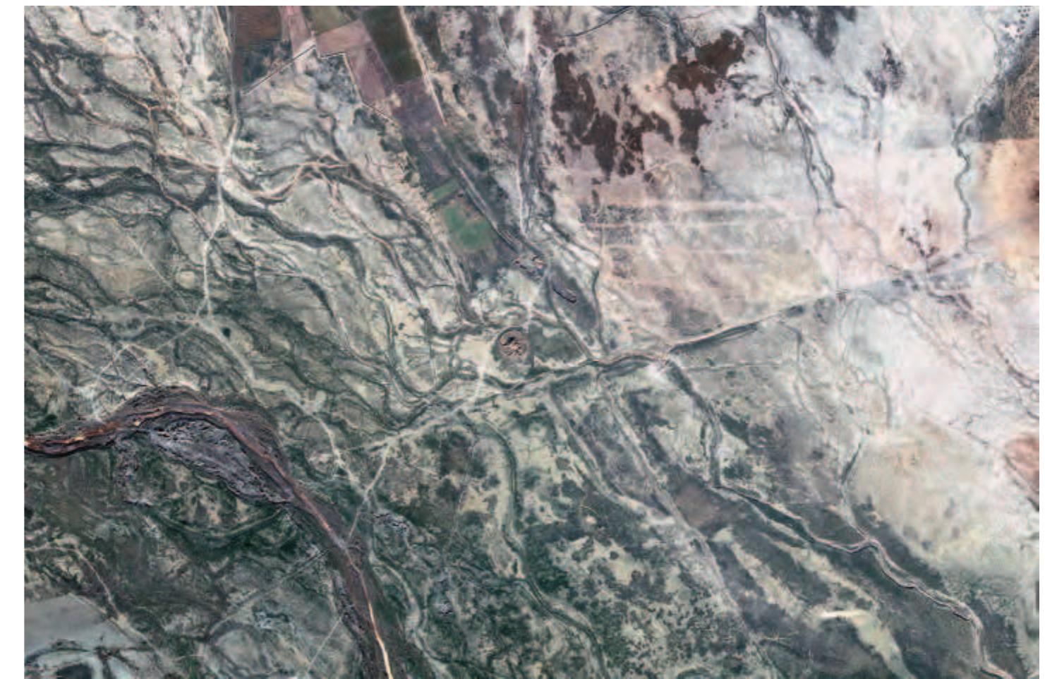 Fig. 4. Satellite view of Haji Khan and its surroundings. A bend of a tributary of the Ghareh Chai River is visible in the bottom left corner. An unexplained linear feature runs diagonally from ENE to WSW just to the south of the site and its circular surrounding  wall. The image is 2 km wide and orientated so that north is at the top. (CGroosle FRarth 4 Tannaryv 2019).  a tempie OF the iviedian perlod was aiscovered. Haji Khan Tappeh (Site A) is located at N 35° 01'58" and E 49° O1' 17'  (UTM 319505 E 3878480 N) at an elevation of c. 1615 m above sea level The site is 2.5 km south of Zaraqan, 11 km south-east of the city of Famenin. and 53 km north-east of Hamadan. It lies in the centre of the Famenin Plain 500 metres north-east of a tributary of the Ghareh Chai River. Prior to the construction of the petrochemical company complex, the tappeh was situ-  ated in the middle of uncultivated pastureland south of Zaraqan village (Figs. 3-4). 