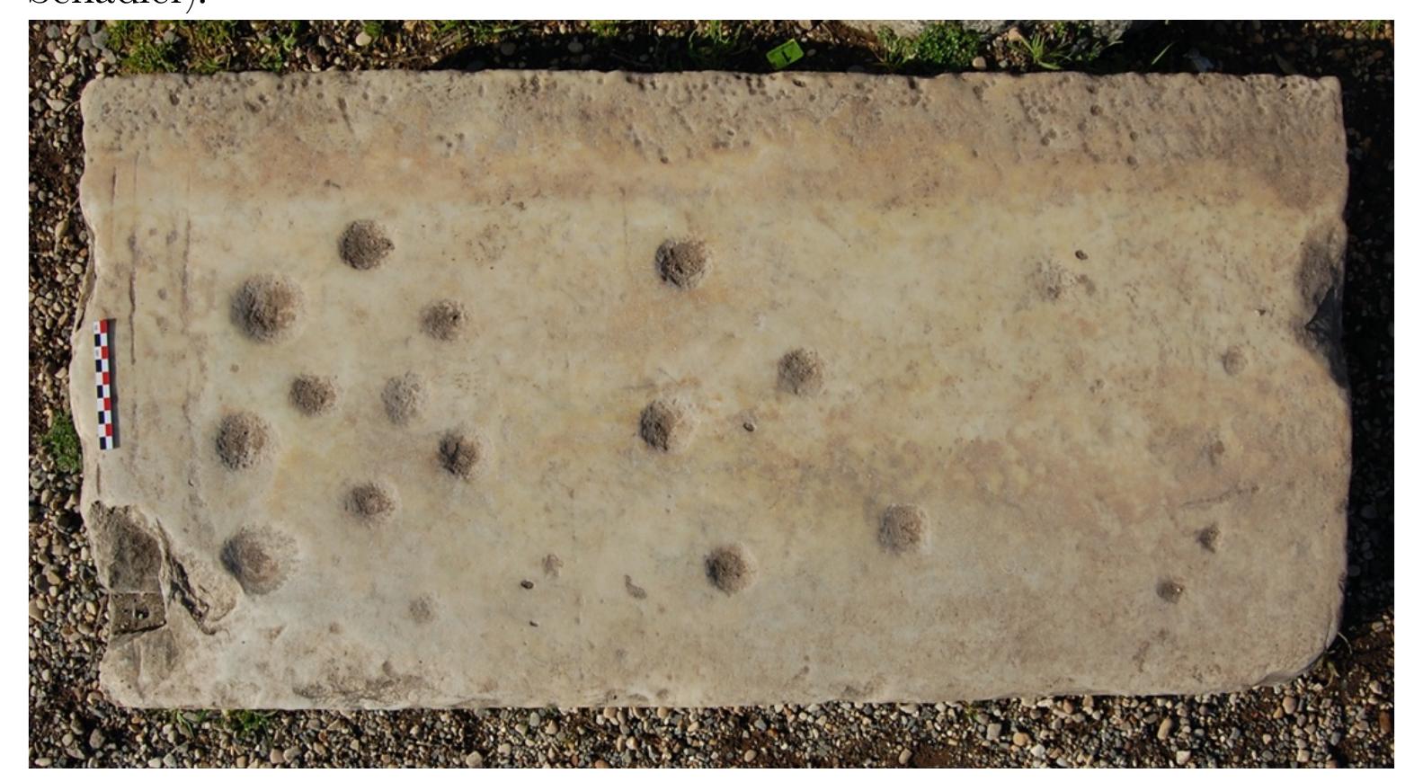 EU AMG TUTE UF UG NT Ba CUPTLEL Uf ULE LIUSULLLU LULU, LUPUTTE ELOTILUILUTT by £LUTILO  A partially preserved clustered marble lane with 13(?) preserved pockets and a double “starting line.” 12 pockets of varying size and depth cluster closely together in close proximity to the “starting line” and are arranged in a broadly linear fashion. One pocket is situated between the double “starting lines” (Unpublished. Photograph U. Schadler). 