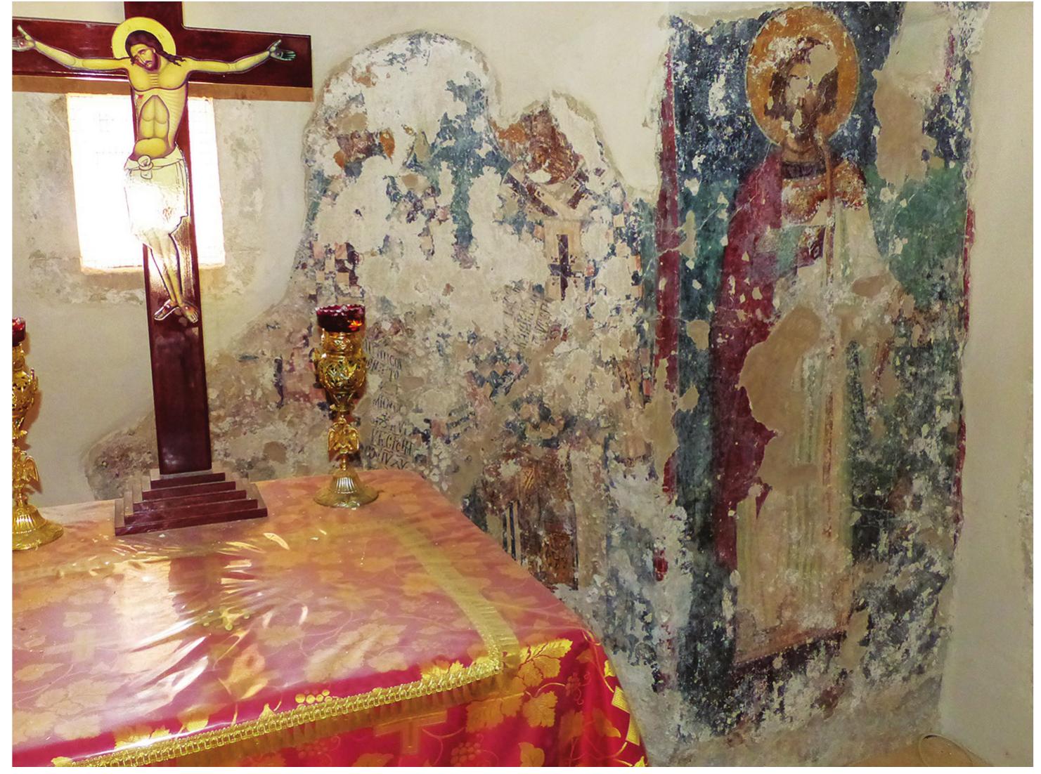 dedicated to St. Demetrios was added to the south.®? Two arches were opened on the southern wall of the old church, connecting the two chapels. The two sanctuar- ies were also connected by a further opening. Finally, the height of the walls of the old church was increased. Today, the entrance to the katholikon is through the bell tower in the northern nave and through the south- ern wall of the southern nave.  In the sanctuary in the right part of the  half-  cylinder of the apse, there are a few remnants of at  least two concelebrating bishops (  bishop, flanking the altar, can be iden  of Caesarea due to  is holding a scroll with a variant of a  his liturgy:7? KA  TOY[TON.] AY MA TOY K[YPIOJY K[AT] | POJC HM | ON I[HCO] TO AE| EN TQ MOT | IPI[ this bread be the honorable Body of our Lord and God and Savior Jesus Christ. Amen ..  C[QTH AMIN  right bis  his dark hair and  TIIHCON | M  Fig. 2). The left tified as St. Basi ong beard.”” He text taken from  EN APTON  TQ T[O} | [T  [(OEO]Y K[AT] Y X[PICTO]Y. Q]...  .in the cup.. hop holds a scroll, the text of which is illegible.  JMION CQ  (And make  .). The  Only the northern chapel was decorated with wall paintings,”° which are unfortunately very fragmentarily preserved.”! The majority of the murals were destroyed during the aforementioned alterations. We do not know how comprehensive the original iconographic program was; what remains is the following.  72 On the iconography of St. Basil, see A. Chatzinikolaou, “Heilige” RBK 2:1041-48; J. Myslivec, “Basilius der Grofe? LChrI 5337-41; and I. Spatharakis, Byzantine Wall Paintings of Crete, vol. 1, Rethymnon Province (London, 1999), 322. 