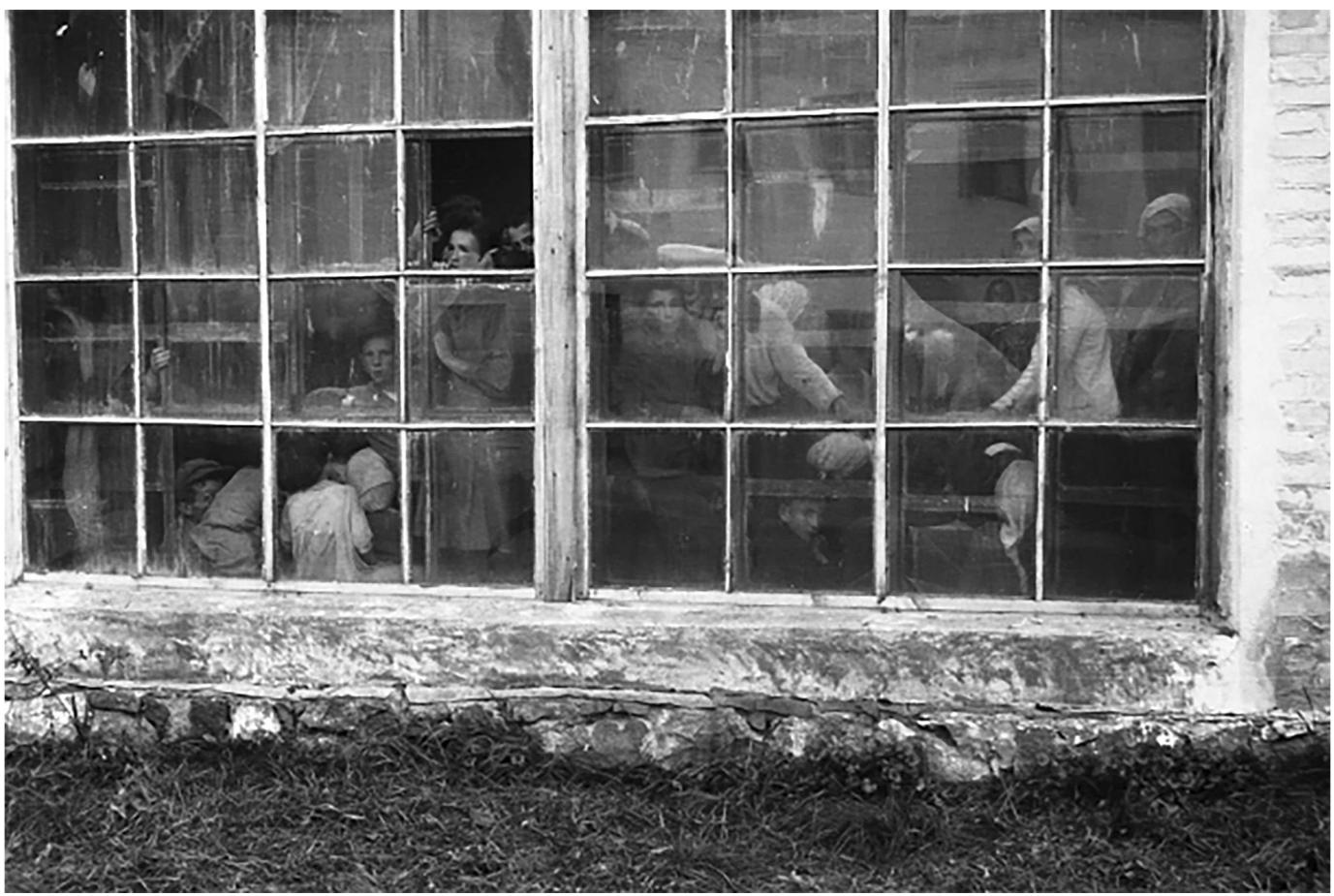 Figure 1: Front side of a photograph taken by Fritz Heinze in August 1941. Building fagade with view of people waiting for their murder in the Western-Ukrainian town of Novohrad-Volyns’kyi. http:/peterthiel.de/kriegstagebuch.htm. 