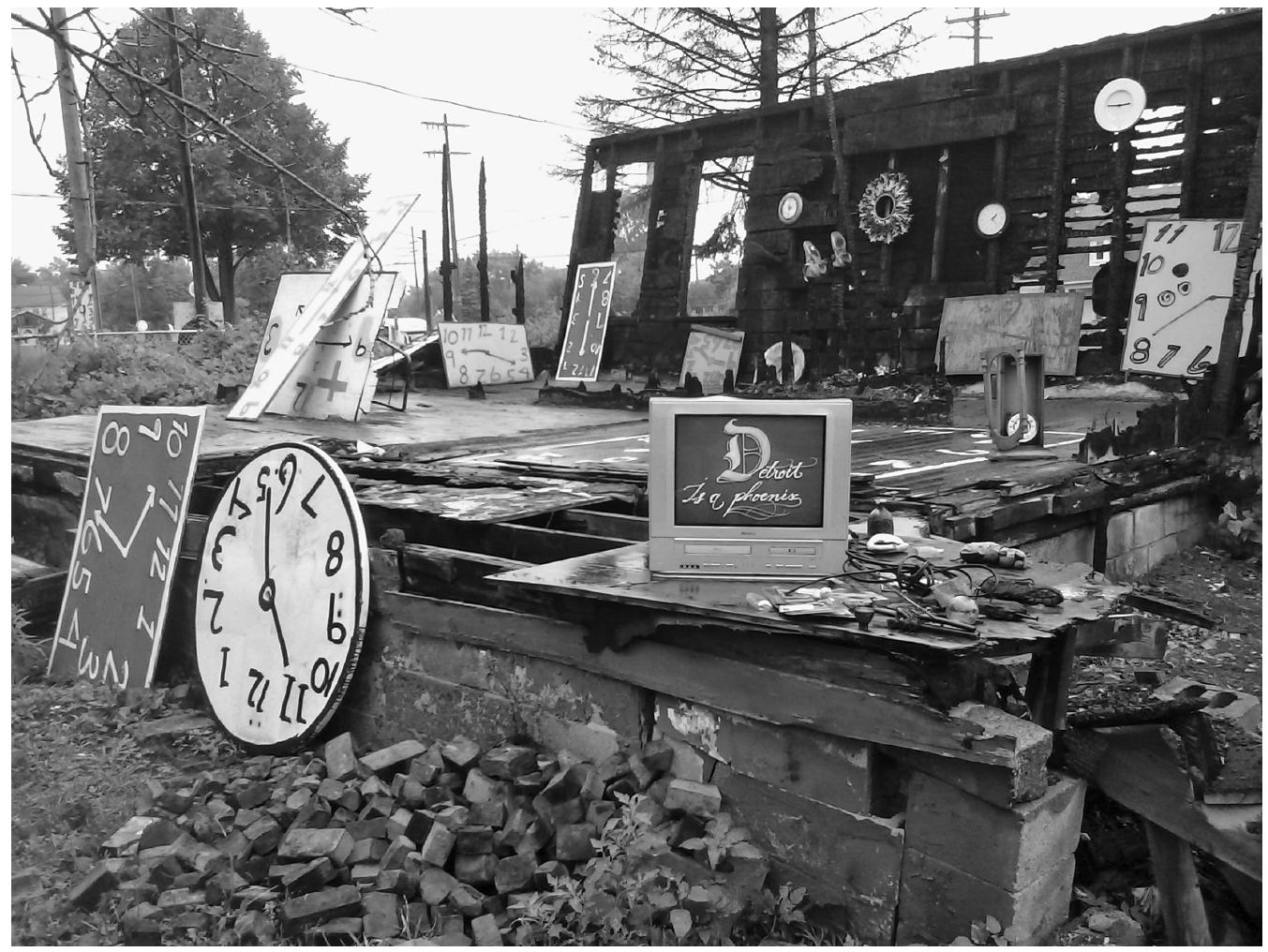 RE6.7 Reused waste, ruined building and clocks painted by the artist in the Heidelberg Project (Detroit, USA). Photo by author.  a? 4 YL ¢  If the entropic character of Guyton’s work is an effect of the interaction between the art environment and the urban environment, in the case of Man’s environment in Camelle, the strong entropic element was the product of the work’s location on the ocean’s shore, an entropic space by definition; the sea brought cultural and natural detritus (industrial rubbish, animal bones and drift- wood) that Man reused in his work and at the same time the sea, rain, wind and salt continuously altered the sculptures, the garden and the rugged coast itself. Entropy, in fact, was at the heart of Man’s art, because degrading agents were incorporated from the beginning: beach sand to make concrete, low-quality paintings, rusted iron, etc. The end of his work came in two phases, first by a  
