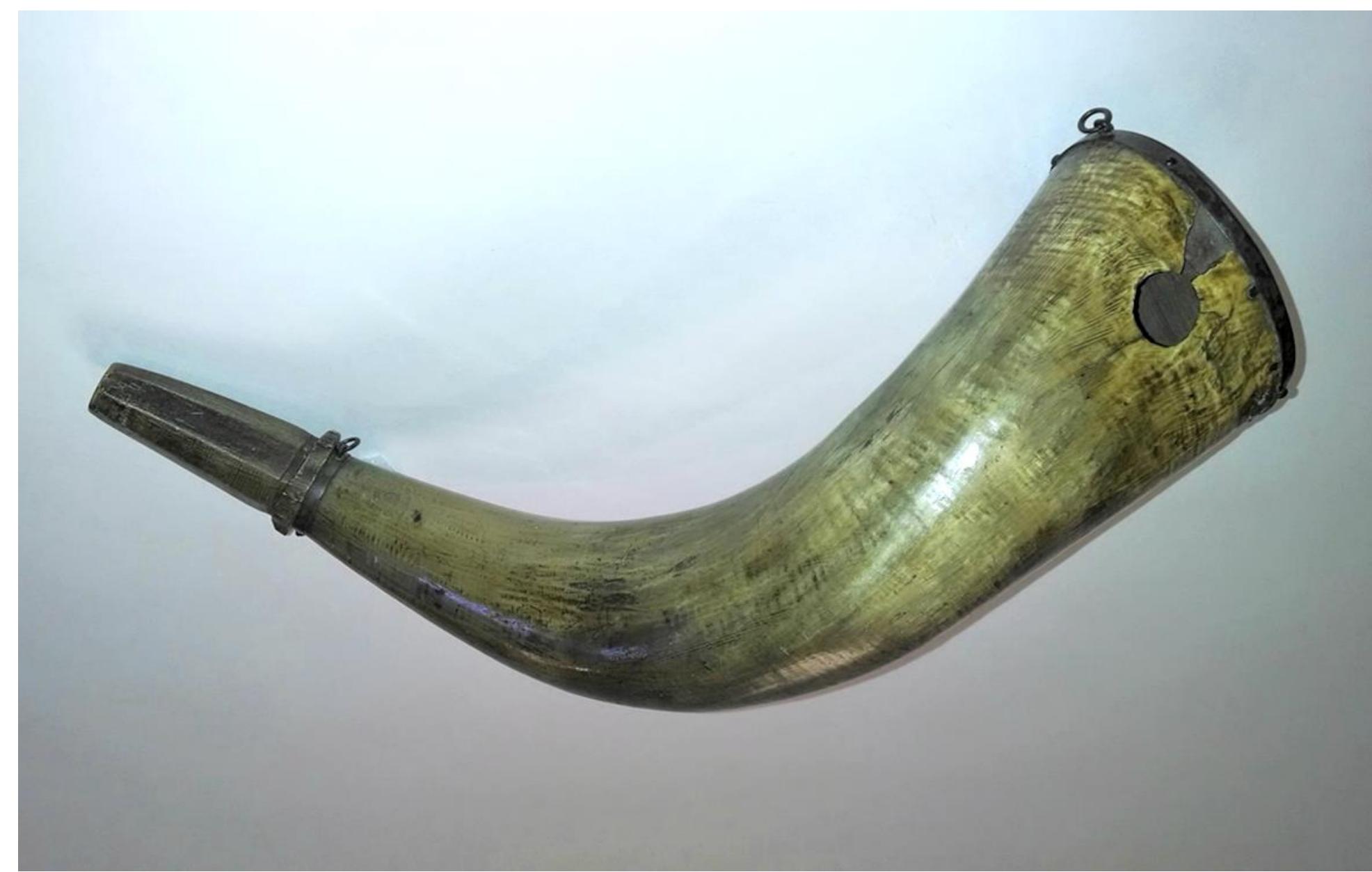 Figure 31. The bullet-struck James Hayward powder horn on display at the Acton Historical Society.  The horn was reconstructed from the fragments collected from around the target site. The shards from the wound track were not used in the reconstruction. The horn’s bullet exit area (approximately 3 inches/7.5 cm by 1.5 inches/3.5 cm) could not be reconstructed due to extreme  fragmentation of the horn into small shards, some of which were carried into the wound tracks (Figure 41). 