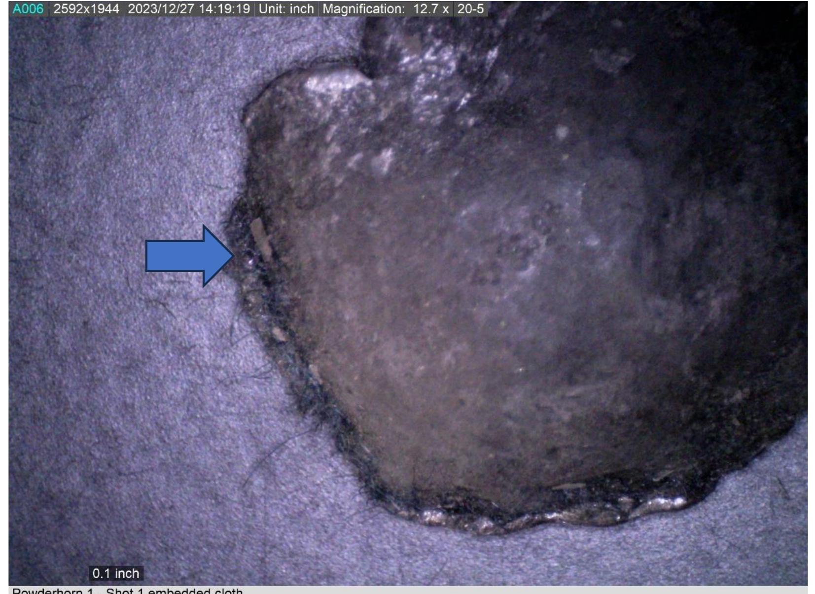 Figure 39. Photomicrograph of the edge of the split ball showing cloth fragments embedded in the lead 