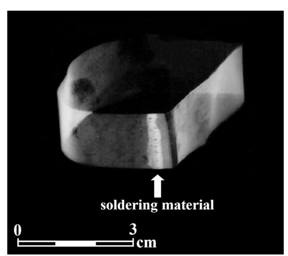 Fig. 18 - Radiographic image of the central part of a brass case showing the soldering material located between the two metal sheets (brass case G, lap joint).  4.2. The Brass Cases  Fig. 17 - SEM images of the hook-and-eye closure after etching showed: (a) groups of slip lines and a long representative inclusion (sample H7, L-CS); (b) higher magnification of the inclusion (sample H7, L-CS); (c) groups of slip lines and a small elliptical inclusion (sample H12, T-CS); and (d) higher magnification of the small inclusion (sample H12, T-CS). 