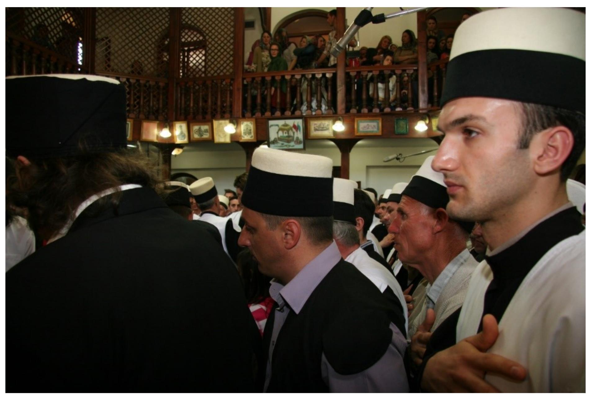 Fig. 3: Observing the Ashura zikr of the Rifa‘l Sufi order from the balcony (front row with green headdress of the Tegeja e Haxhi Shejh Iljazit in Rahovac, western Kosovo. Photo © Mustafa Aslanovié, 2013 