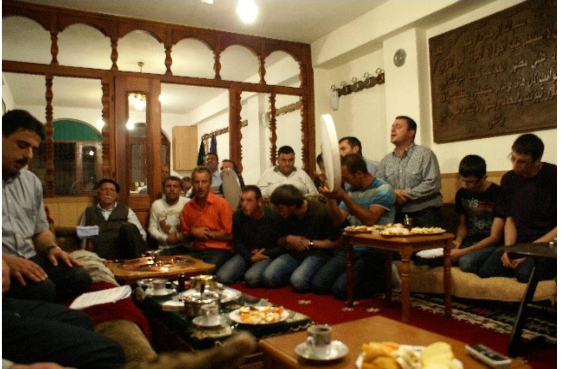 Fig. 6: The Rifa‘I Shejh Mehdi Shehu and his murids routinely gather for the recitation of devotional songs (ilahija), Teqeja e Haxhi Shejh Iljazit in Rahovac, western Kosovo. Photo © Sara Kuehn, 2012.  ntricately interwoven with diverse sensory elements, culminating in a synaesthetic crescendo. Beyond these pivotal ritual ceremonies in Sufi communities, the shejh and his murids routinely gather for the recitation of devotional songs (ilahija), which serve as a conduit for storytelling. Through these melodious expressions, narratives unfold, shedding ight on the profound connections and relationships between the Prophet, Sufi saints, and ocal dervish figures recognized as ‘friends of God’ (evlija) (Fig. 6). 