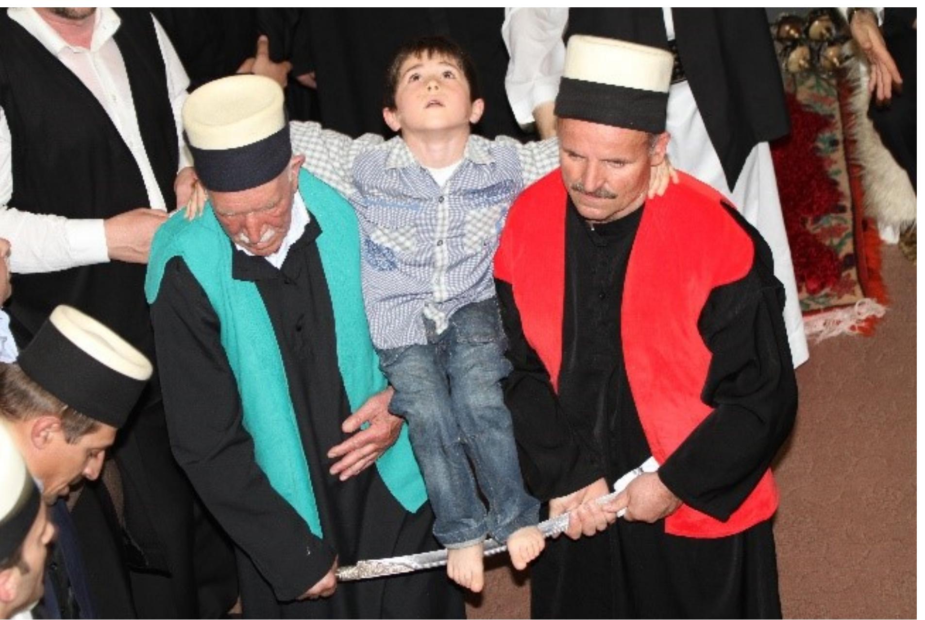 Fig. 10: The youngest son of Shejh Mehdi, with his bare feet on the sharp blade of the sword, paraded arounc the sema’hane by the dervishes, symbolically enacting Husayn and Hasan, Tegeja e Haxhi Shejh Iljazit in Rahovac, western Kosovo. Photo © Sara Kuehn, 2013 