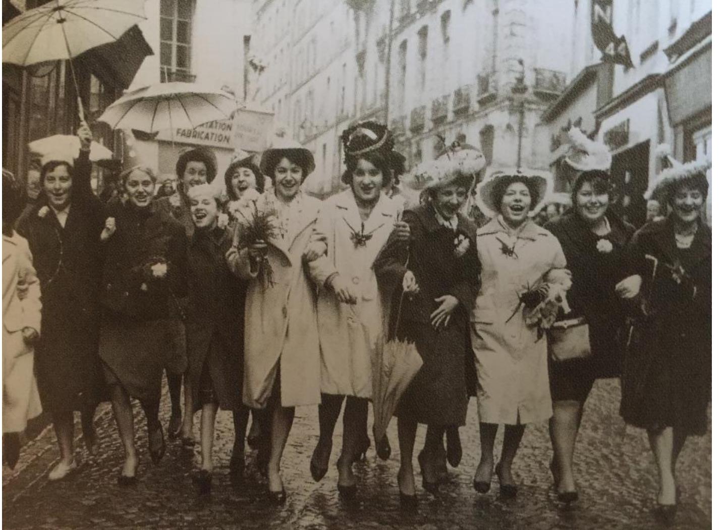 Figure 6: Catherinettes marching in the streets of Paris, 1962 © Dorothea Nicolai (Foto taken from the CTHS article by Anne Mojaret at the Bibliotheque des Arts Appliqués, Paris)  On the 25'" of November the Catherinette is the “queen” of the atelier. She is “crowned” with the hat her colleagues have been preparing for her without her knowledge. She is congratulated by the head of the atelier, maybe one of the famous couturiers. The atelier is decorated and a table prepared for a common meal. There are fotos showing the whole tear of famous Paris fashion houses in costumes. There was dancing with music, sometimes little show performances. 