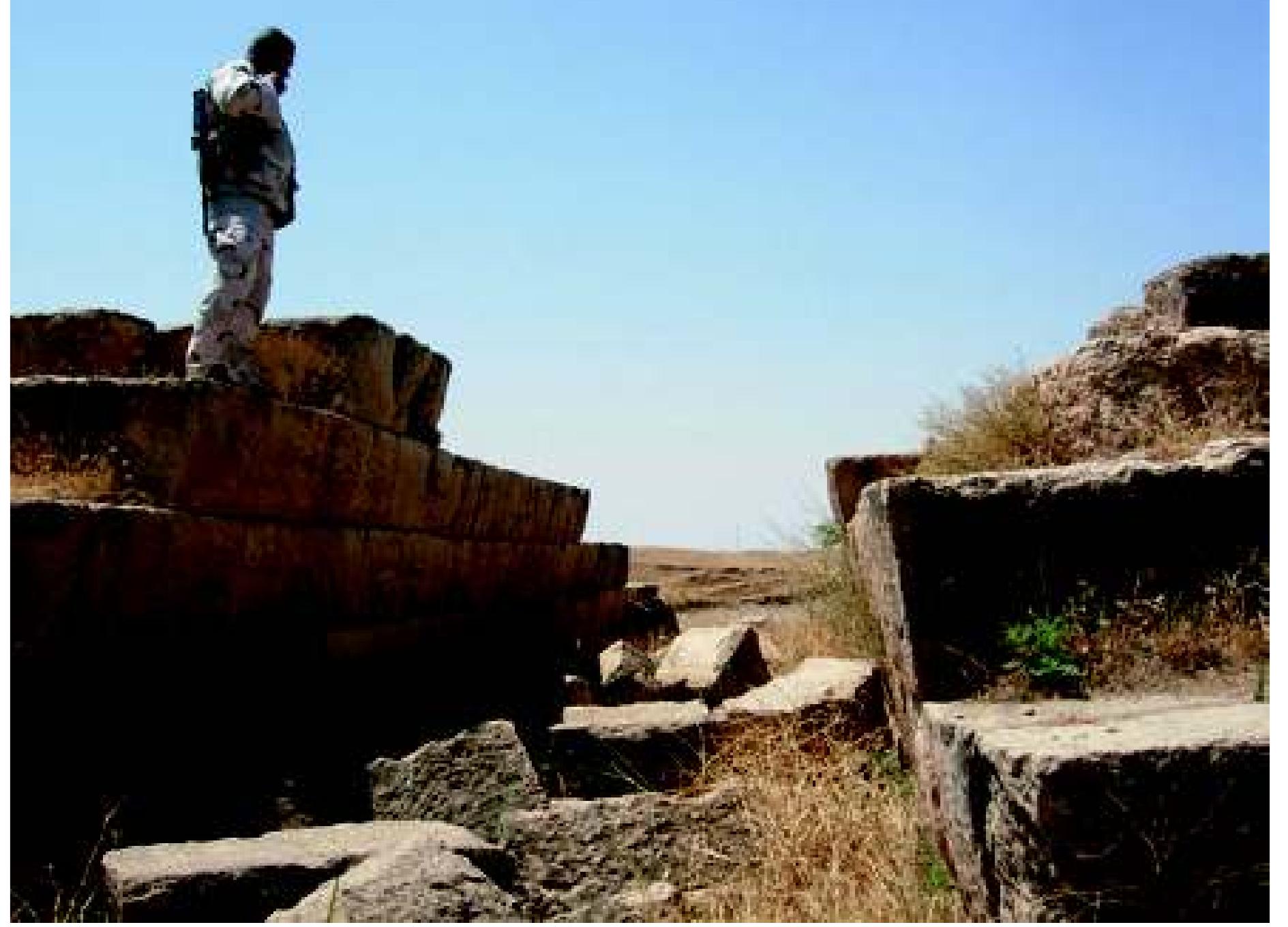 Fig. 3: Jerwan: Neo-Assyrian arched aqueduct. Photograph: authors, June 2009  More extensive information about ancient settlements in Navkur, taken from field surveys in the 1940s, was later made available in two Iraq government publications in Arabic. As these are scarce and seldom cited, they are briefly summarized here; much of the same information is repeated in English, with further discussion, in Han- noon’s unpublished dissertation (1986, 187-280). Navkur was then divided by local government boundaries be- tween, west of the Khazir, the central nahiya in the gadha of Sheikhan, province of Ninua (file dated November 1943), and east of the Khazir, the nahiya of Al-’Asha’ir as- Sab’a (“Seven Tribes”) in the gadha of Akre, province of Duhok (file dated December 1949). Navkur is therefore   In July 1850 Layard (1853, 367), while travelling between Jebel Maqlub and Akre, noted that several mounds on the way “bore marks of having been tapped by my industrious agents, but none appeared to contain ruins”, i.e. easily recognisable walls. E. A. Speiser, as quoted by Barton (1927, 16), passed through Navkur in May 1927 on much the same track, examining “several interesting mounds” on the way. King (Bachmann 1927, iv) had also remarked: “T found fragments of inscribed bricks built into the walls of houses in villages near [the Khanes canal], so I think a careful survey of the district would well repay the time and rouble.” A large fragment of inscribed brick said to have been found at Tell Gomel is now displayed in the Qachakh Culture Museum, but the inscription shows that it was originally intended for the city of Khorsabad by Sargon 721-705 BC) and the date of its arrival at Tell Gomel is un- known; we are indebted to Irving Finkel and Jon Taylor for his identification.1  