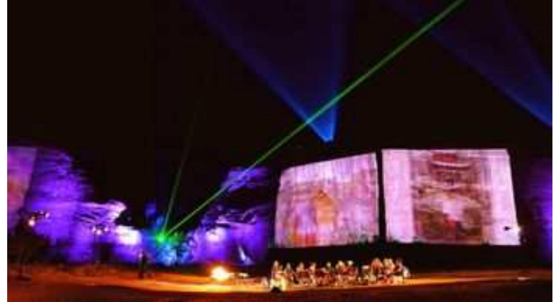 FIGURE 7. Still image from Yahoo!'s time capsule “launch” at Jemez Pueblo, New Mexico. Resembling more of a Pink Floyd laser show- cum-Burning Man spectacle, the image content of the time capsule is projected onto the red rock walls of the pueblo. Photo: Rob Lee. 