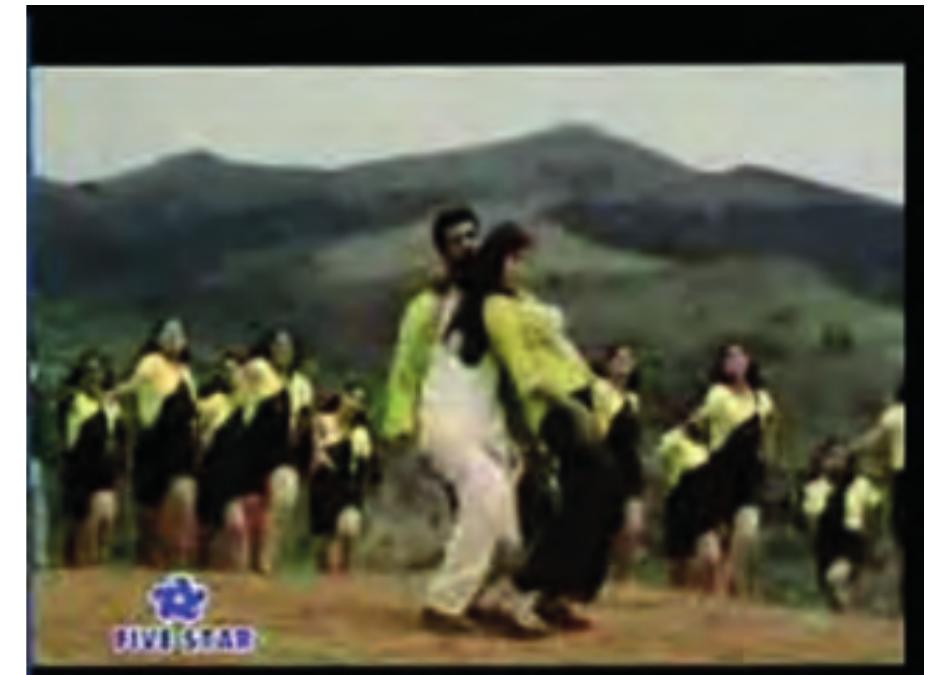 The leading couple with their entourage  www.youtube.com/watch?v=wyp7D2Nzib0.  The original video depicts a song and dance scene with a large group of young women and men on a green mountain slope. The song and dance number represents the flirtation and woo- ing going on between the two main characters. The lyrics of the Tamil song Kalluri Vaanil in the original film, their English translation, and the buffalaxed subtitles can be accessed at http:// Www .voutuhe._com/watch 2v=awvyn7DINZib0. 