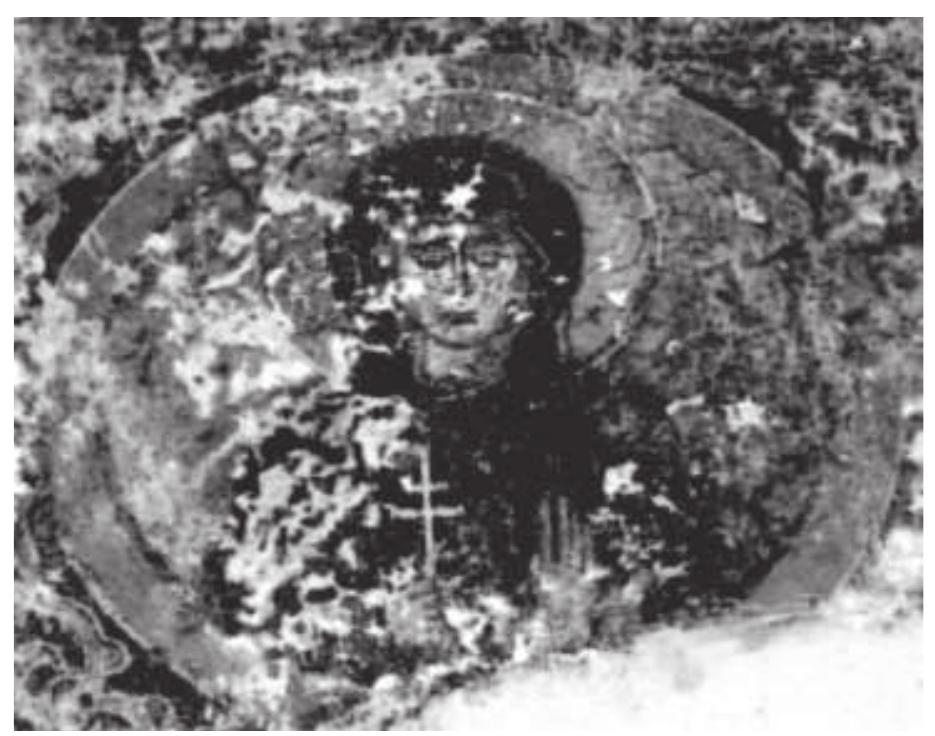 Fig. 7. Foutia, Ayios Yeoryios, Portrait of a saint  Special details in the wall paintings of the group, always within the framework of the artistic manner of rendering forms in this period, are ren- dered in a similar more or less awkward way. There are the oval, elongated faces with voluminous hair, the delicate figures with cylindrical necks and the relatively lowered but often expanded shoulders, as well as the similar sense of the third dimension and of weight. The eyes, with their intense look and shadows, allow the eyelids to come through, while the nose is long and narrow, ever so slightly hooked, whereas the mouth is small with stressed lips; the lighted chin protrudes, and the ears are rendered either with curved lines or with strange oval shapes. 