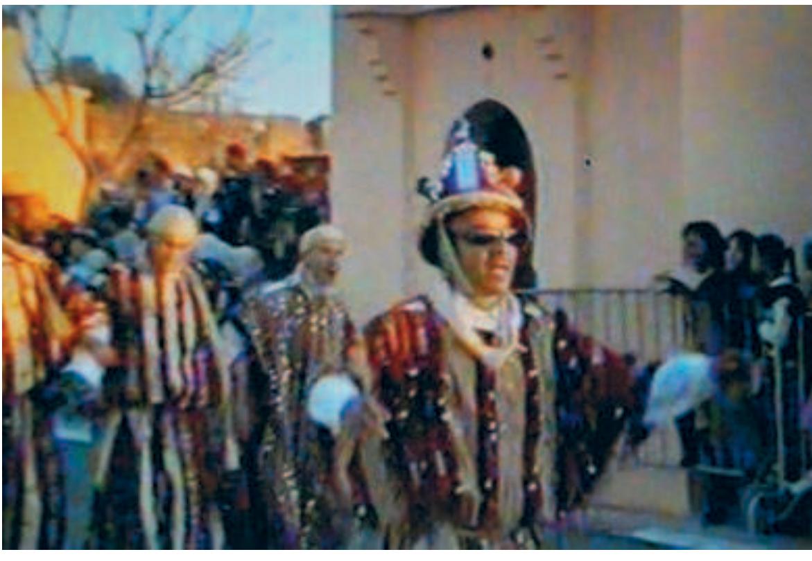 A jackal performing “folklore” heads an urban congregation of the ‘Isawa. Procession in front of the king on the occasion of the Prophet's birthday, 2006 (filmstill). Note his hat with the electric bulbs. Courtesy Muqaddim Abdelhaq al-‘Awad. 