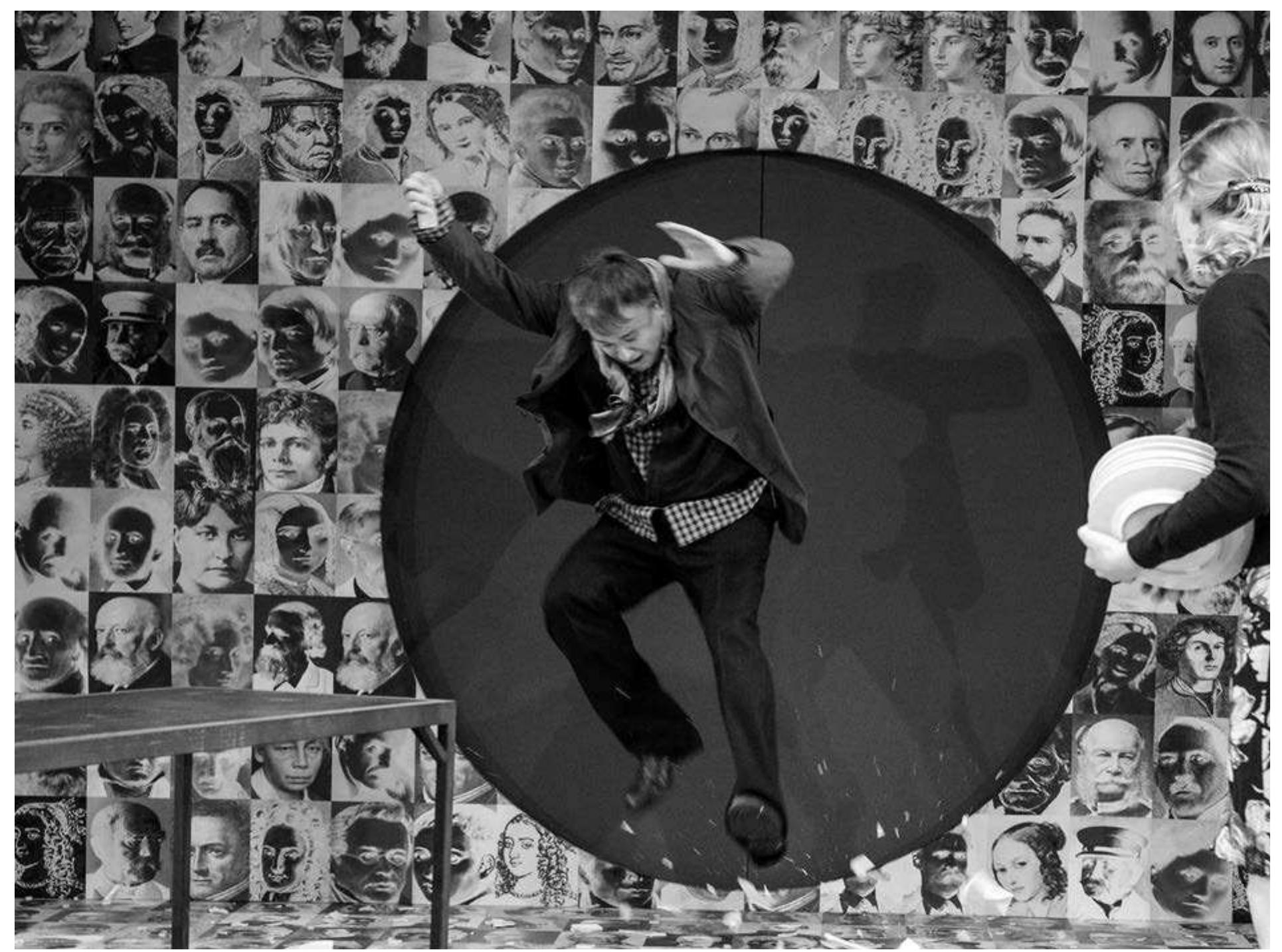 Carl Sternheim's Die Hose / Burger Schippel, directed by David Mouchtar Samorai. Recklinghausen, 2013. Photo: Marion Buehrle.  Carl sternneim's Die Hose / Burger ochippel, directed by Dai Die Hose / Burger Schippel, the Ruhrfestspiele and Staatstheater Nurnberg's mash-up of two Carl Sternheim comedies adapted by David Mouchtar- Samorai. The walls of the set were filled with photographs, some in negative, of various respectable members of society from throughout history. This served as a constant reminder of the world the would-be gentlemen in the play wished to enter. At the rear of the stage was a circular door in this wall of respectability. The door could be opened or sealed off at various times, sometimes granting entrance, and sometimes as a means to expel interlopers.  