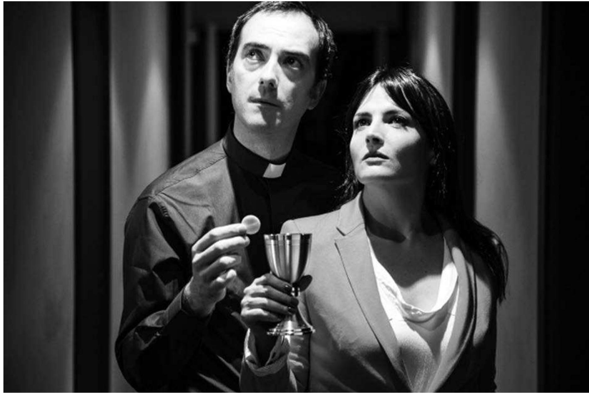 La visita by Antonio Mufoz de Mesa. Photo: Courtesy of Uroc Teatro.  In another visual index of passing time and shifting relationships, the priest drinks more and more wine—from a holy chalice—and munches communion wafers. After saying no to alcohol in  La visita, directed by the author and produced by his wife, features a cast of two: the priest (Ivan Villanueva), who is in charge of a Catholic school for boys and a summer camp, and a woman insurance agent (Rosa Mariscal), who for some dozen years has handled policies for the diocese. At the outset, the priest establishes his superior position by insisting that she call him "Father," she addresses him with the formal you (usted) while he speaks to 
