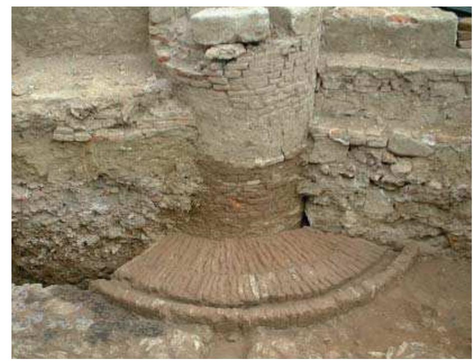 Fig. 3.58 Excavation of Palazzo Scotto. The well in the XIV century square. Of note, the continuous rising that the well underwent until the XVIII century.  3.57). The first, as already seen, were situated in public squares or widenings, whereas the second were generally located behind buildings, at times covered by roofs and paved with floor bricks, and the last were near or in the middle of workshops. Technologically, wells were cylindrical structures made of reused bricks held together with a firm (non hydraulic) mortar, until reaching deep groundwater. Since used continuously, they were often raised and the well curb had to be moved to adjust the entrance to the rising ground surfaces. They were often provided with one or more external footboards, which were round or concentric and made of bricks laid edgeways and arranged in a radiating pattern (fig. 3.58). The most complex case is the well found at Palazzo Scotto. It?” is part of a 