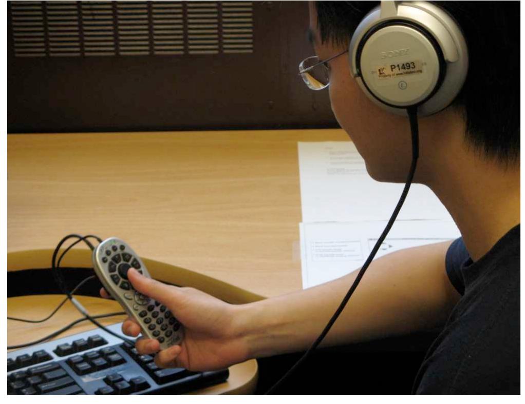 Figure 4. Experimental setup  The hardware set-up is as follows (see figure 4). A Mavael Keiboard equipped with an Intersense Inertia Cube3 (IC3) for 3- DOF gesture tracking and button interaction has been used. For this experiment, the sound sources were pre-setup. To guarantee an authentic distance effect each individual sound stream was pre- recorded very close to the speaker and at the same time from a distance of about three meters. We chose to use binaural processing on stereo headphones, with the application of HRTFs from the fmod sound library’. A pre-study showed that the distance effect in the recorded files was not perceived to be very distinct. Paying particular attention to preservation of intelligibility we post-processed attenuation and reverberation to achieve a clear, recognizable distance effect.  