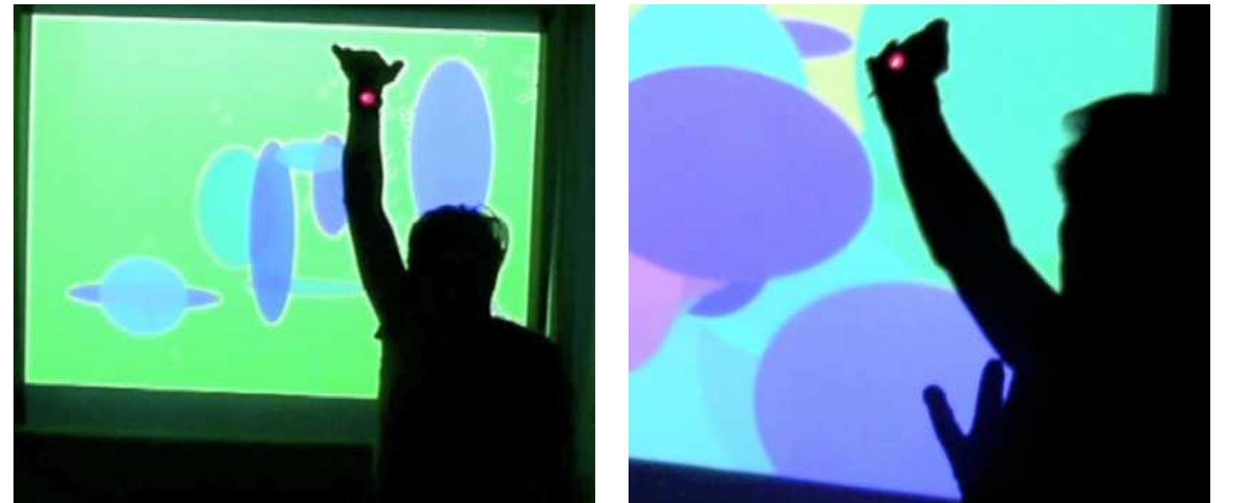 Figure 2. Stills from “Firefly Fury” (Marathon Demonstration), filmed on June 18, 2012, at the Columbia Computer Music Center, Columbia University, New York. The picture on the right shows a higher density of foreground ellipse because the right wrist is  flexed outward, as compared to the picture on the left, where it is flexed inward. Photos by Danielle Y. Robinson. View at http://  vimeo.com/fluxations/ff.  Figure 1. Stills from Montreal Comprovisations No.1 and 2, filmed on June 15, 2012, at Skin—Surface—Circuit: Embodying the Improvisatory, ICASP-McGill Center for the Critical Study of Improvisation Interdisciplinary Conference, in Montreal. The first photo shows a blue-oriented bubble explosion in progress; the second shows one red-oriented bubble explosiion in progress ir  the upper left and another just begun toward the center of the screen. Photos by Stephanie Khoury. View at http://vimeo.com,  fluxations/mc1. 
