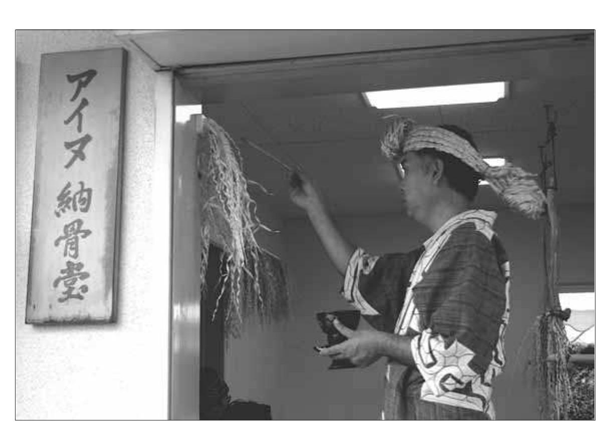 Fig. 3. Ancestral memorial ceremony: An Ainu man offers rice wine to a deity of the charnel house to request another year of protection for the bones of Ainu ancestors. Hokkaido University’s Faculty of Medicine keeps the charnel house locked year-round except for the one-day me- morial ceremony. 
