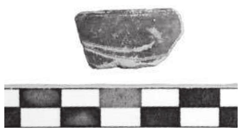 Fig. 9. Rim fragment of a cup with incised decoration in West-Slope style (Find no. 15364.18).  bance. Three stamped tiles, one of which carries a stamp with the letters ETIITAMIA®YA |... ], were found in the vicinity of the proskenion.*° These roof tiles differ in shape and fabric from other tiles in the area of the theatre; they most likely originate from a Hellenistic building situated elsewhere in the city and were brought to the theatre to be re-used in a roof construction there. A stamp with the let- ters [... TAMIA... ] preserved has been reported from the area of temple B on the acropolis, and similar types have been found at the early Hellenistic peristyle build- ing. Although no wall structures were observed in the area of the western parodos, the tiles might have belonged to a roof covering the parodos that perhaps belonged to a later house, or that might have served as a cover for a working area. A few nails that may have originated from a wooden construction might also indicate the presence  of a roof cover. 