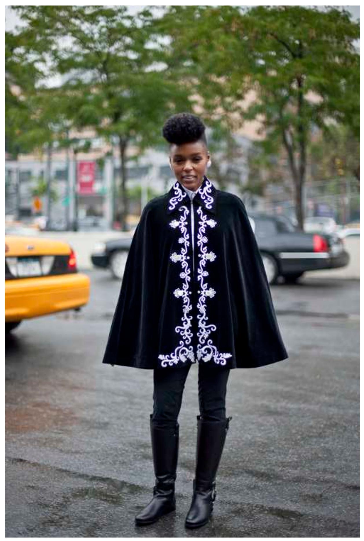 FIGURE 6. JANELLE MONAE SHOULDERS THE CAPE. PHOTO: JANELLEMONAE.COM.  —  Monae has also set a new standard in reworking the Afrofuturist inheritance. During he: performances of “Tightrope”, she accepts a cape brought to her on-stage, as if shouldering the mantle of James Brown across generations and genders (see fig. 6). 