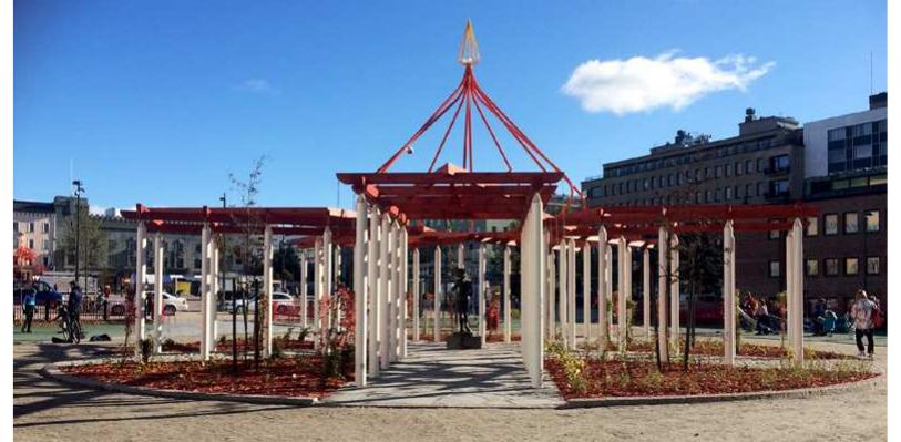 Figure 8 — Artwork on the western end of the market square frames a statue of a young woman. (Copyright: The author)  Figure 7 — The idea to represent the general layout of the excavated village with plot borders and buildings by altering different kind of paving was not realized because of accessibil- ity. Symmetrical squares and straight lines create harmony to the market square today. (Copyright: The author) 