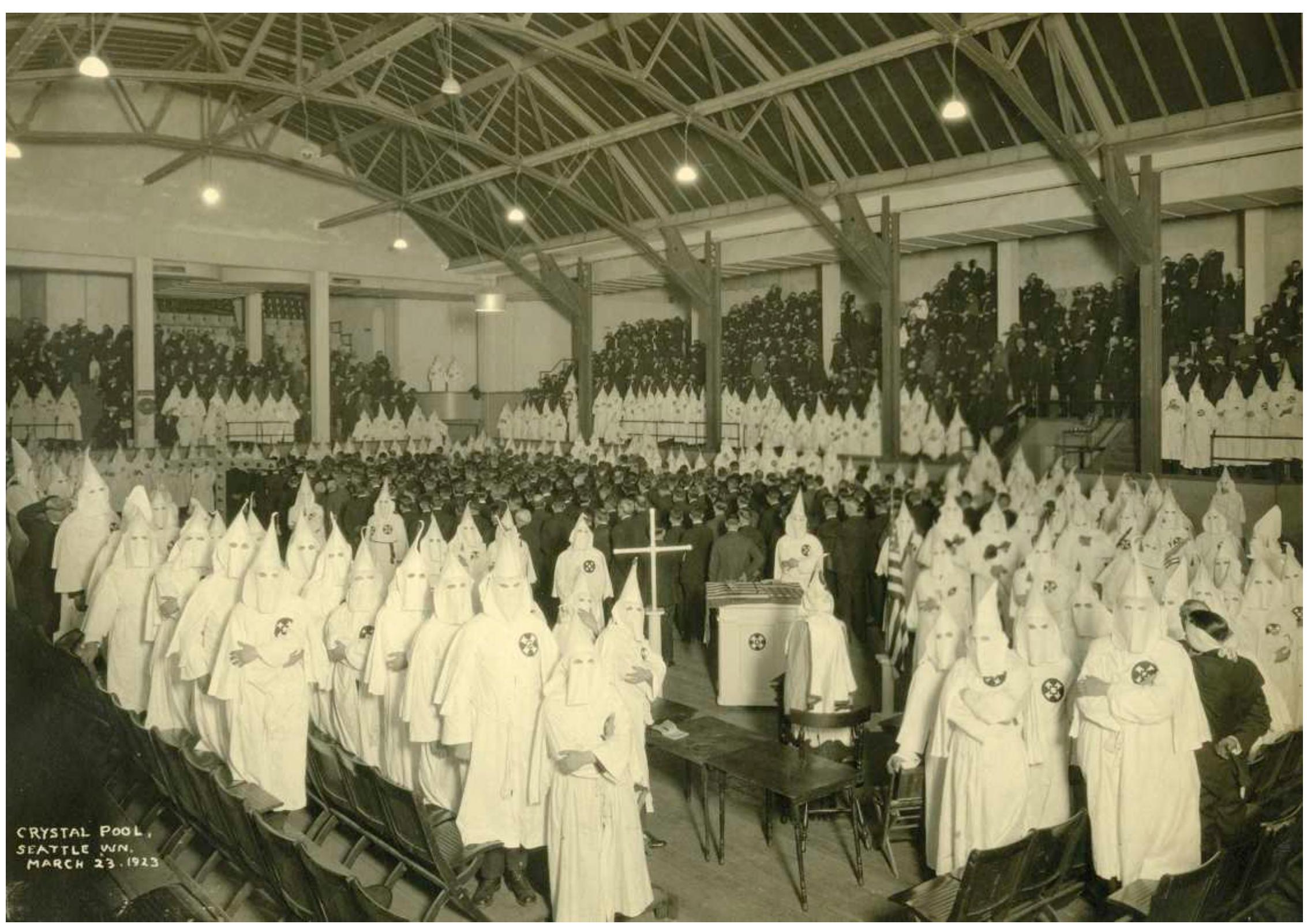 Figure 3. Founded in 1915, the second Ku Klux Klan promoted white, native-born, Protestant supremacy. It campaigned for immigration restriction, booste enforcement of prohibition laws, and viewed Catholics and Jews as mortal threats to the American republic. Seattle Klan No. 4, shown meeting here it March 1923 at the Crystal Pool, near the group’s downtown office, was founded in 1922 with two thousand members. Note that all unrobed attendee: facing forward are covering their faces. The Klan exhibit of the Seattle Civil Rights and Labor History Project is one of the project’s most visited features http://depts.washington.edu/civilr/kkk_intro.htm (Courtesy of Washington State Historical Society) 