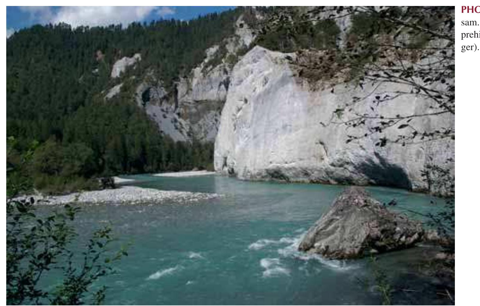 reach is the 2.5-km long Mastrilser Rheinaue. Downstream of the Ill confluence, the shape of the channel cross-section becomes a double-trapezoid. The width of the main channel decreases downstream from 80 to 40 m; distances between the flood embankments vary between 200 and 400 m. Alter- nating bars are lacking because of the reduction in slope, sediment caliber and channel width.  channel widths originally ranging from 120 to 400 m. Today, channel morphology and plan view of the Alpine Rhine primarily reflects the comprehensive river engineering works of the 19—20th century aimed to provide flood protec- tion for agricultural land and human settlements (Vischer 2003). The channel has a trapezoidal profile (width at the base 100 m) with a boulder riprap protecting the base of flood embankments between the confluences Rhine—Land- quart (20 km downstream of Reichenau) and Rhine/TI1 River (66 km downstream of Reichenau). Alternating gravel bars with backwaters are a typical morphological feature of this reach (Photo 6.3). The only remnant of the original braided 