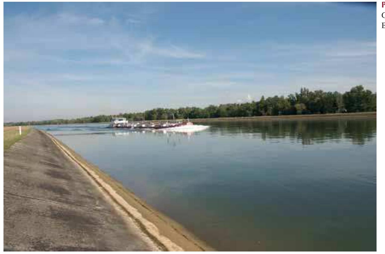 remain in the old Rhine (IKHR 1993), which accelerated t  lowering of the water table. In the 61-km long reach down- stream of the Grand Canal, four additional power plants were  completed between 1963 and 1970. The loop diversion d  sign of these plants, which leaves the water in the riverbed for  most of the reach, was intended to mitigate the rapid loss the water table. Continuing erosion problems resulted in t  ne  e-  in he  construction of two additional power plants (run-of-river  plants without loop diversion) at Rkm 209 and 335. Dow  n-  stream of the last power plant (Iffezheim), ~180 000 m gravel must be added annually to the river to prevent further  channel degradation (IKSR 1993).  After 180 years of river engineering, the Upper Rhine is primarily a straight single-thread river with uniform cross- sections, protected banks and dikes (Photo 6.7). All the islands except for a few large ones disappeared. Near power plants, dikes top over the adjacent former floodplain by >10 m. Bed sediments include gravel in the upper reaches, and fine gravel and sand in the former meandering reach. Channel widths range from 130 to 300 m between Basel and the last power plant, 250-300 between Karlsruhe and Mainz, and from 350 to 500 m between Mainz and Bingen. The width of the uniformly deep navigation channel within the channel varies between 100 and 450 m. 