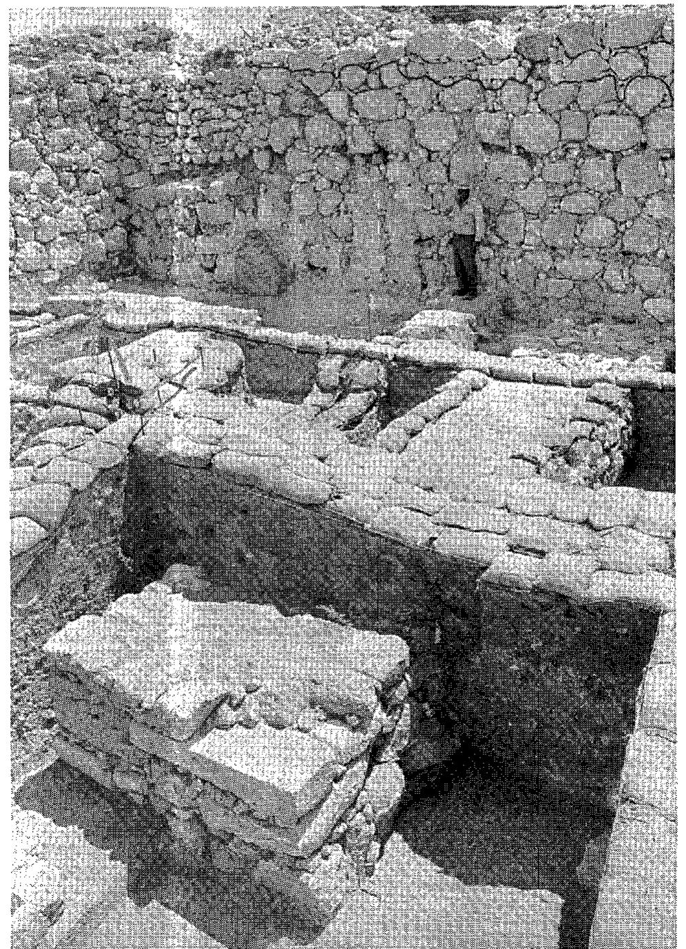 Fig. 35. The right jamb of the entrance to the outer gate courtyard, from southwest. Note at back the outer revetment wall with its upper three courses restored.  segment of the Level If Wall 769, we reached the conclusion that the lower part of the latter wall segment is mostly earlier than Level II, almost certainly forming the left jamb of the Level III outer gatehouse. We could not dig there and learn more about the entrance to the Level III outer gate, as the structure was superimposed by the Level II outer gate. Above the burnt bricks uncovered on top of the eastern end of the Level III tower’s stone substructure we still identified a few boulders of the eastern facade of the superimposed Level II tower (Wall 9502 in Fig. 30). Its orientation slightly differs from that of the underlying Level HI tower. This is undoubtedly the left tower of the Level II outer gate which parallels the ‘guardroom’ (Locus [E.18:C]) — the right tower of the gate. Both towers were built with the same orientation; but while the right, eastern tower was well preserved, the left, western tower was mostly destroyed and its stones eroded down the steep slope.  tower was mostly destroyed and its stones eroded down the steep slope. 