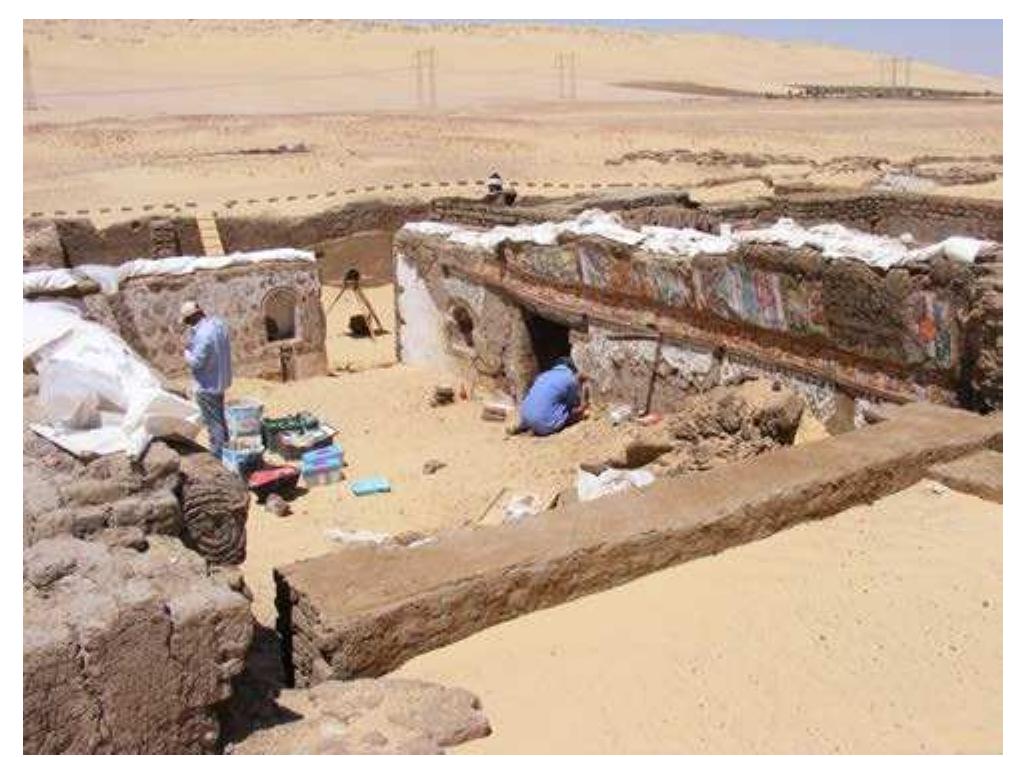 Figure 2 Room no.7 , building no.1, during excavation, photo to the north -west (Courtesy of IFAO).  On the south side of the room, the vault bears the representations of a series of characters in which one can recognise two of the founders of Bawit monastery and nine prophets, each of whom holds a scroll inscribed with a passage from their prophecy. The base of the vault is decorated with a frieze of meanders alternating with birds. The wall itself is decorated with a pattern of diamond shapes each holding a green leaf. Another geometric pattern, covered with large blooming flowers, is painted on the west wall. The east wall, of which only the lower part remains, holds three niches. The decoration of the largest, set in the middle of the wall, was found in the debris. It depicted Christ surrounded by seraphim and the symbols of the four evangelists. 