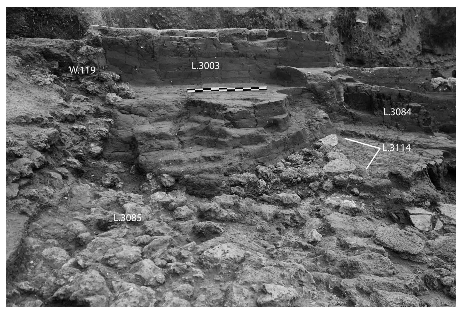 FIG. 17. Southern mudbrick tower (L.3003) of phase RG-4b gateway. Arrows point to plaster (L.3114) separating phase RG- 4a additions (L.3083 [L.3084]), view to the west-northwest (JCHP photograph 2012-P0922). 