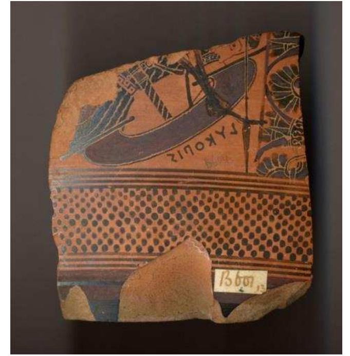 Figure 37. Fragment of Attic back-figured dinos depicting an Amazon fallen in battle, named ‘Lykopis’ in the painted inscription next to her shield. Probably from the sanctuary of the Dioskouroi, c. 575-560 BC. British Museum, 1888,0601.442.  Figure 36. Attic black-glazed cup fragment with incised Cypro-syllabic inscription, c. 420-400 BC. British Museum, 1900,0214.17. 