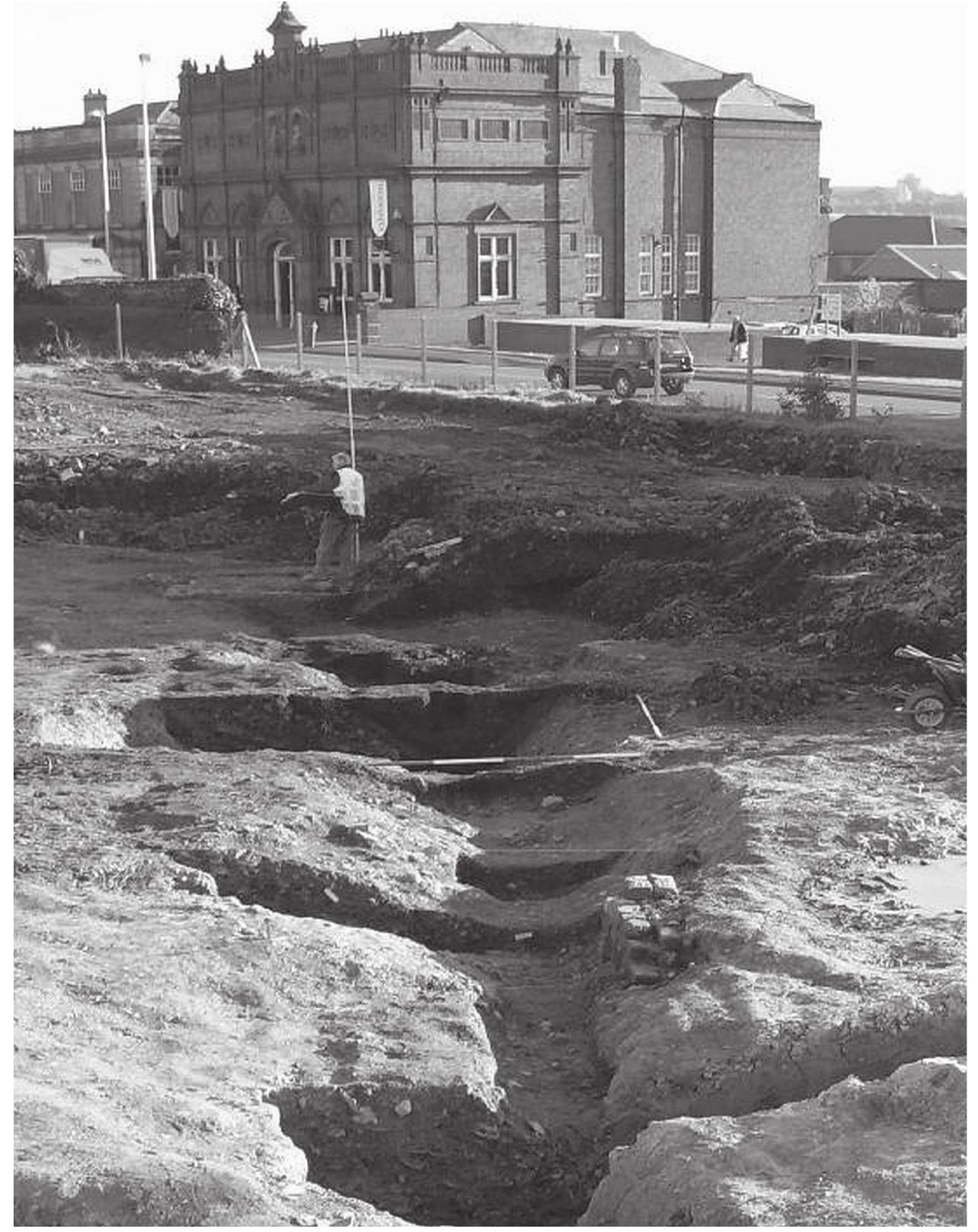 in width - in places just a narrow gully, elsewhere opening out into a wider channel or pool. Its fill was packed with ceramic waste material. The elongated pit with narrow gullies at either end, the half-sectioning of which was discussed earlier, could now be seen to be part of this watercourse. 
