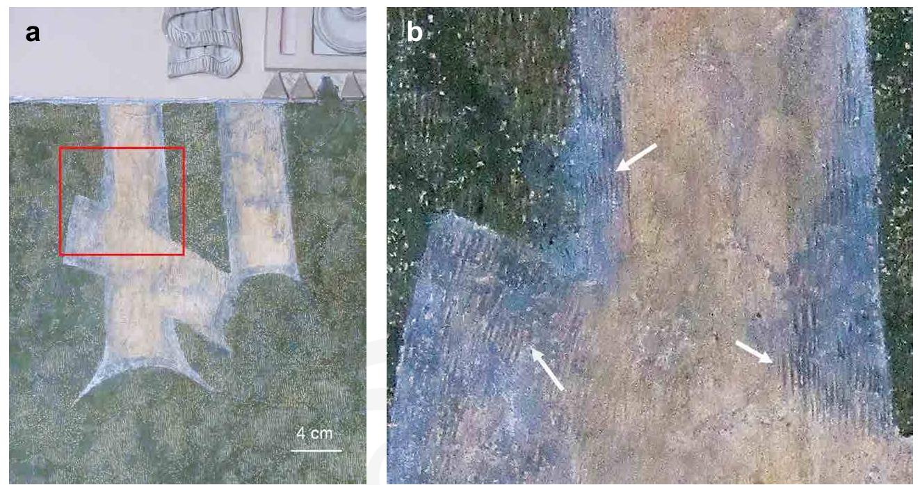 Figure 4.12. (a) Alteration of lead white, creating a shadow effect, observed on the edges of a P letter; (b) details of repainting (indicated by white arrows) the same P, applied in the course of the conservation campaign of 1989-95. Photos: Chateau de Germolles, 2015. 