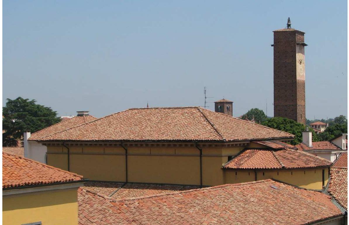 Figure 2: The Great Hall photographed from south-west. We can see the hipped roof of the hall and the roof of the apse shaped as a truncated cone with a single pitch covering the former skylight (photo by E. Zamperini).  ~*~  The pronaos has an autonomous gable roof; the apse has a semi truncated conical roof end- ing at the top with a skylight now covered with a single pitch with curved tiles; the lateral bodies are single pitched, in the back of the hall they are connected to the roof of the rest of the building, in the front they end with a hip; the roof above the properly called hall is a hipped roof. Since the other parts of the roof are not accessible and of minor constructive im- portance, the paper will focus on the hipped roof of the hall. 