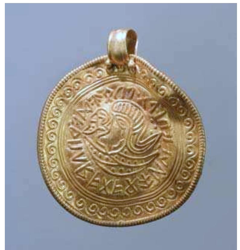 Figure 9. A gold bracteate (diameter 30mm) found on top of a building floor to the west of the cult house. The bracteate shows a human figure surrounded by a runic description that does not form a reasonable sentence. It dates to the Migration period (photograph by B. Almgren).