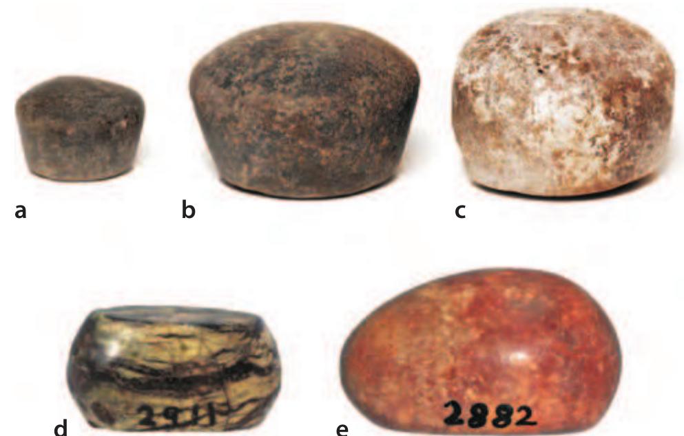 Figure 12.9 Weights from Naukratis: a—c three Egyptian stone weights: (a) 2 gedets and (b—-c) 1 deben, Bolton Museum, 1925.20.1—3 (Photo: © Bolton Library and Museum Service); d bronze weight with Greek letters inlaid in silver, Oriental Institute, University of Chicago, E3025 (Photo:  © Oriental Institute Museum, University of Chicago.);  e small discoid stone weight: half a shekel, Oriental Institute, University of Chicago, E2911. (Photo: © Oriental Institute Museum, University of Chicago.) 