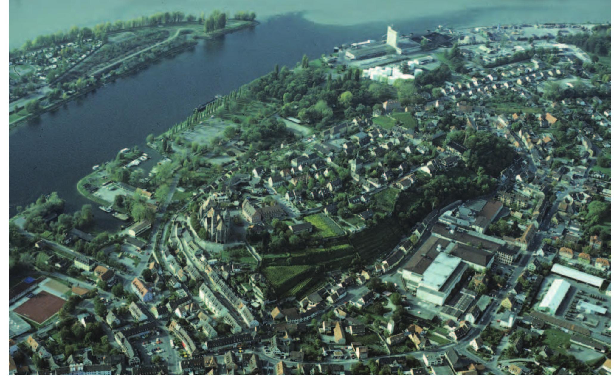 Figure 6.6. The Miinsterberg of Breisach, seen from the southeast to the northwest, on the left side the Rhine (Landesamt fiir Denkmalpflege im RP Stuttgart/O.Braasch).  One might suspect that it would be easy to make a linkage between outstanding graves and their related settlements, with the aid of imports. In actual  fiocnscnwarzwald, baden-VVUritemverg)  The Miinsterberg (Fig. 6.6) overlooks the Rhine at about 45 m asl, offering a panorama from where the Vosges can be seen in the west, the Black Forest in the east and south, and the volcanic region of the Kaiserstuhl in the east. The 10-hectare basalt plateau has been intensely inhabited until the present day. Excavations have shown several metres of settlement deposit, arranged in a deep tell-like stratigraphy. Almost 250 pits, silos, traces of pithouses and houses from Ha D1 to LT B have been found. At its peak (Ha D3), the whole plateau was occupied (Fig. 6.7: green), starting in the southern half of the hill and retreating back into the same area (Balzer 2009; Balzer 2010;  