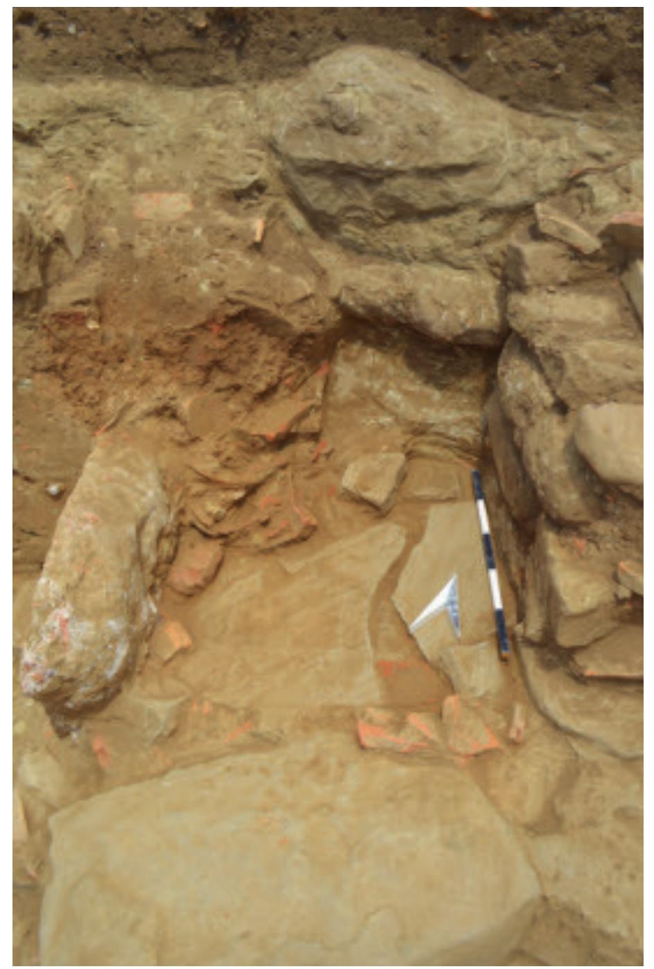 Fig. 13. Fragments of cooking ware found in situ next to the cooking installation (Soren Handberg).  was paved with flat stone slabs of irregular size which have only been preserved underneath a tile layer in the northwestern corner of the platform. In the corner of the mortar slab and the bedrock west of the stone structure, several sherds of Hellenistic cooking-ware vessels were found lying right on top of the pavement of the platform (Fig. 13). This area was covered with many fragments of roof tiles, which must have preserved the vessels in their original place. 