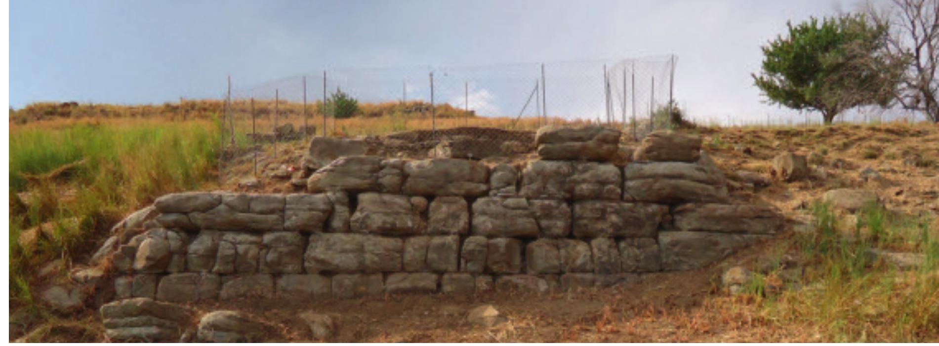 Fig. 18. The outer face of the Lower Acropolis wall seen from the south (Soren Handberg).  In 2015 another trench (Trench H36) was opened in Area II to the south, as a northern extension of Trench H30 at the fortification wall (see below). Here the end of the street with the staircase was found (Fig. 17). The street runs into a T-junction that connects to another street which presumably ran along the interior side of the fortification wall that encircles the Lower Acropolis plateau. The street is lined on both sides by walls. The eastern wall is slightly broader than the western wall, a fact that could suggest that the eastern wall belongs to a house construction, whereas the western wall might be a lower wall that only served to delimit the street. The two border-walls of the street do not run exactly parallel to each other, and the street is wider at its southern part where it connects with the other street. In the street that runs southwest-northeast along the fortifi- cation wall the excavations reached the level ofa pavement, which consists of numerous stone slabs of various sizes. Towards the south the street is delimited by another wall, which appears originally to have had an opening that was subsequently blocked by smaller stones.  Fig. 17. The two trenches (H30 and H336) at the Lower Acropolis wall seen from the north; the T-junction of the  ope eg: ee OD = Be he = ee ce ee OR Sis eS | ee  Acropolis wall seen from the north; the T-junction of the 