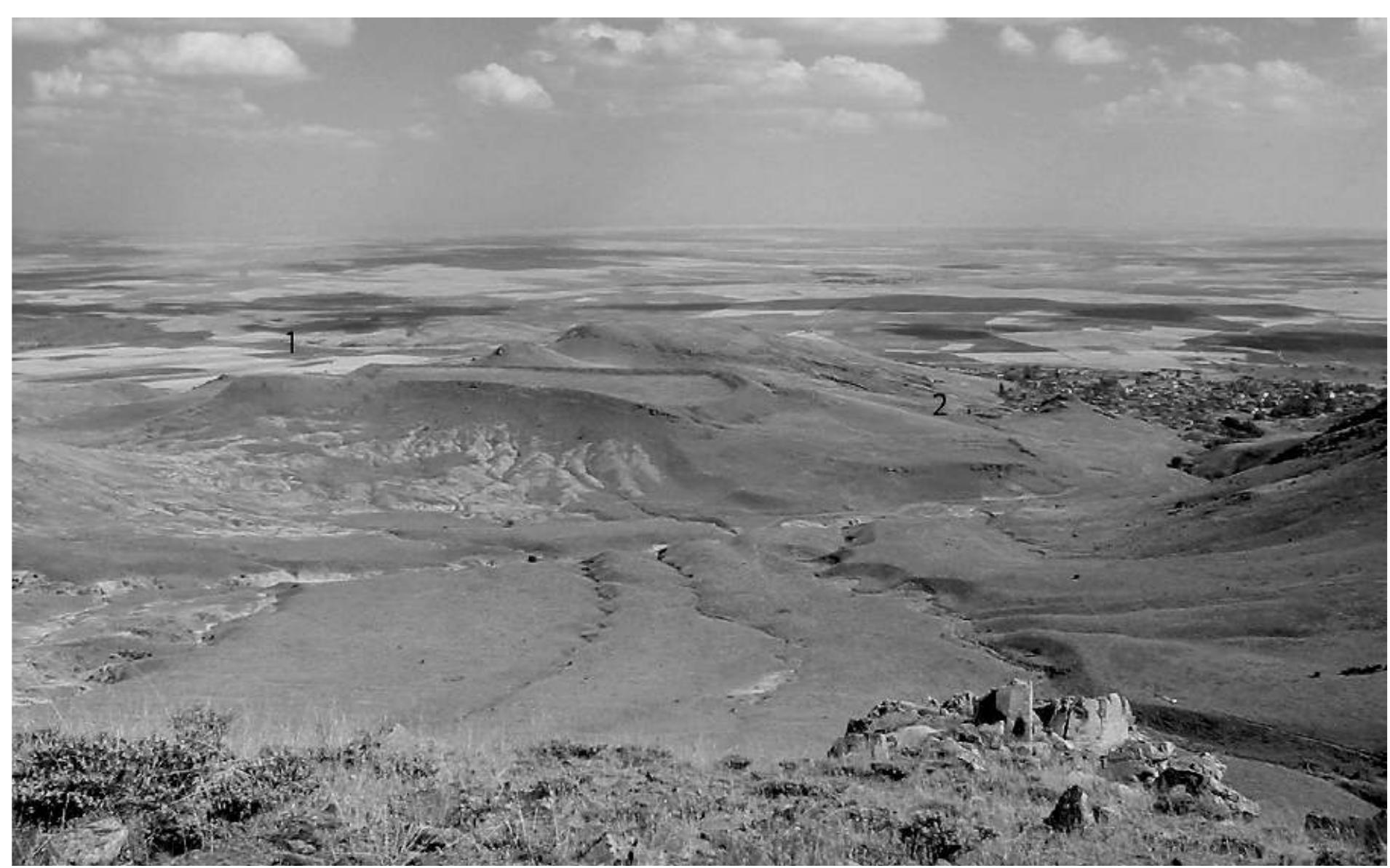 Fig. 9 : Cevre Kale from Kirklar Tepe. The citadel is below 1, the lower Iron Age settlement below 2, Yarasli village at right. 