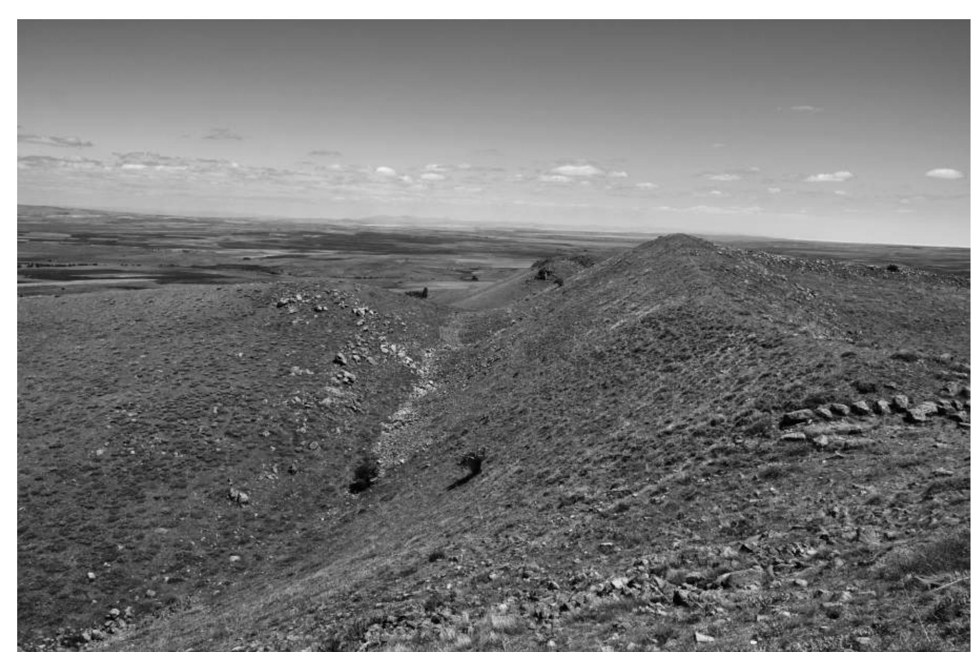 Fig. 11 : The rampart on the west side of the citadel with the ditch below. Stones at centre right marking the junction of the citadel to the main fortress rampart are perhaps a secondary feature. 
