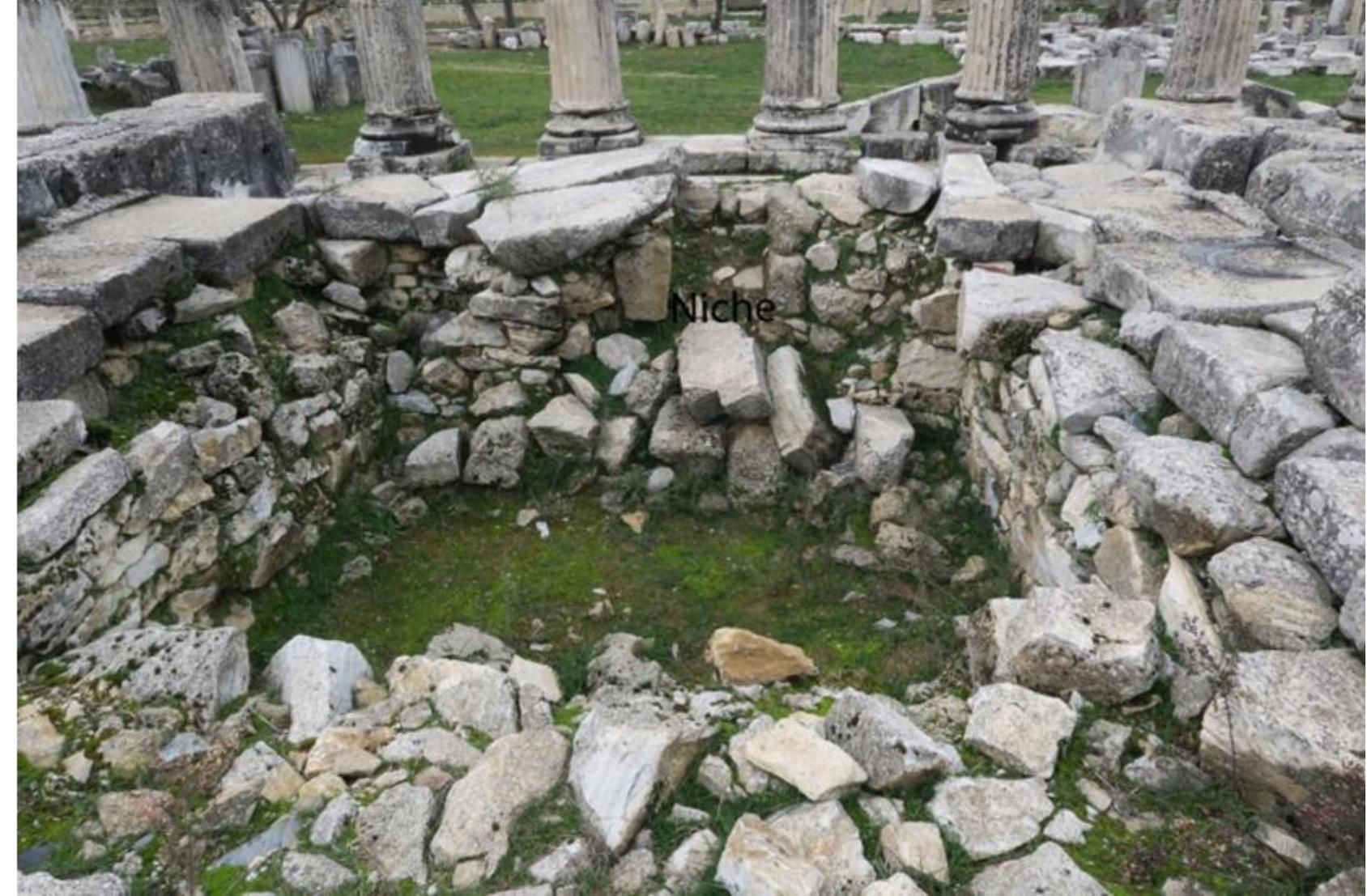 Figure 12: Niche on the south wall  niche coincides with the place of the cult statue also suggests that it is a conscious application that is beyond incidence supporting the existing sanctity. The findings and niche strengthen the possibility that there was a temple or an altar here. Piles of ash detected in the naos excavation, the pieces of the partly burned figures, and glass fortune stones in large number, gold objects which were used as dress ornament in rosette form, ivory ornaments and a large number of coins were probably dedications left to this sacred place. Acquisition of so many small finds in a narrow area is a sign of this. In this case, the wall inside was built to establish the borders of the sacred building in the period when the temple with Corinthian peristasis was built. The walls were raised to the level where the naos flooring stones would sit and inside the naos was filled with rubble stones and soil and infrastructure were established for naos flooring blocks. Wall height was equalized on each facade, the paving blocks were first placed on them and thus naos the level of the elevation was adjusted. The debris fill is not placed in a certain order in the upper level and it forms a plane made of large blocks of carved surfaces and rubble stones. The mortise holes on these blocks, whose surfaces were bush hammered, must have been opened to fix the naos flooring blocks. The difference in elevation between pronaos and naos must have occurred due to this. It seems that this early space is the basis for the location of the temple and especially the sizing of the naos. Although a totally independent building was constructed, the temple was built on the basis of the old building. The temple was Pseudo-dipteral, the reason for the unusual 8 x 11 ratio we have characterized as unusual among the planned temples, because it was built by considering the boundaries of the old building of the temple. We see the closest example to the short edge long edge ratio in the Hekate Temple is Labraunda. In the Zeus Temple, which had peripteral plan and Ionic peristasis, there were 6 x 8 columns and this is unusual for a temple with a peripteral plan especially considering the period it was constructed in. P. Hellstrém explains this situation with the Ion peristasis added around the Archaic temple*°. There is a similar situation for Lagina. The simple dimension of the temple or altar in the 4th century BC was replaced by a larger, more magnificent building with Corinthian peristasis in the Hellenistic period.  