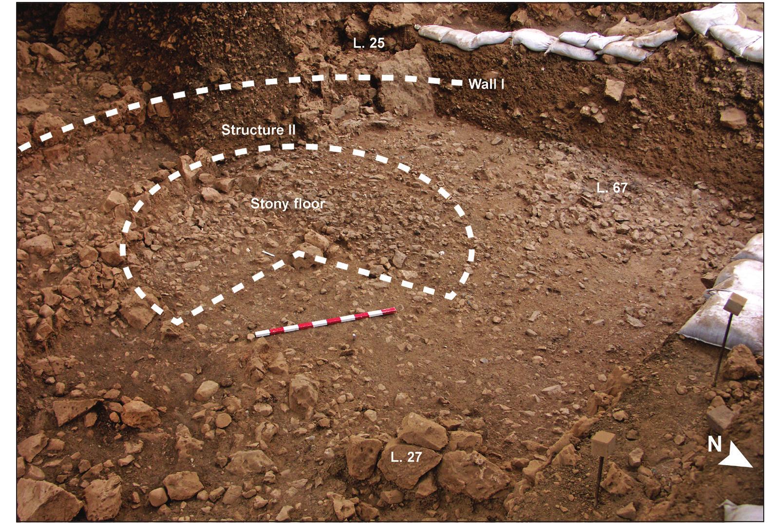 Figure 2. The south-western part of the excavated area, Phase W-7 (a view from the north- east). Several partially preserved stone structures and stone-rich ‘living floors’ were excavated in the area enclosed by Wall I (before excavation of the O5 section).  The architectural complex in the LEN phase is composed of a nine meter long curvilinear wall (Wall I) encompassing a sequence of at least eleven habitation levels, each defined by a thin stony floor (Phases W-6 and W-7; see below). In the area enclosed by Wall I, several partially preserved stone structures and stone-rich ‘living floors’ were excavated (Figs. lc, 2). The structures’ contours were defined by the outlines of the walls and the spatial extent of the stone-rich levels, some of which clearly abut the walls. The stony and stone-poor matrixes inside the Wall I complex contain a very high density of finds, at least some of which (the animal remains) indicate they are in primary deposition and were taken to represent non-clearing of habitation refuse (Yeshurun ef al. 2013, 2014a). The stony floors, stone features and artifact  concentrations were recorded as consecutively numbered  concentrations were recorded as consecutively numbered  We excavated in thin spits (5 cm or less) and attempted to 