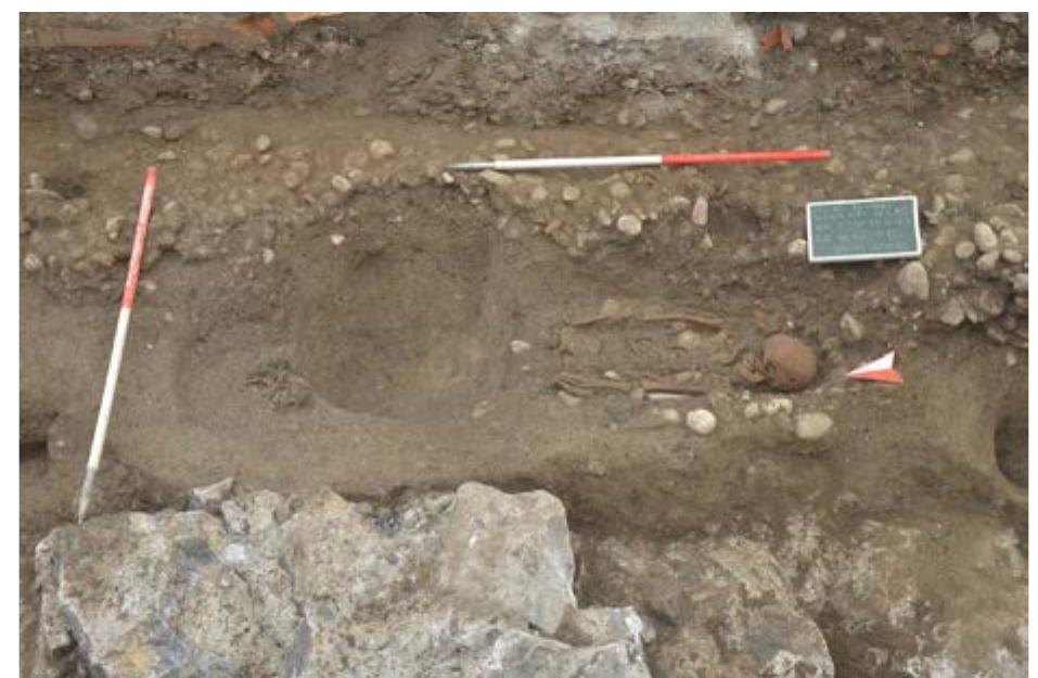 Slika/Figure 6 Stovenska cesta 2014, pokop 7002, inbumacya brez pridatkov, vRopana v severno ypadnico (arbiv MGML). / Archaeological excavations on the north  part of the street Slovenska cesta in 2015: burial 7002, inhumation without grave goods, entrenched in the Emona  northern artery (MGML archives). 