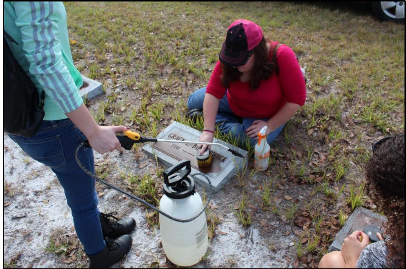 Figure 3: With permission of the owner, students clean gravemarkers using a soft-bristled brush and D2 Biological Solution. 
