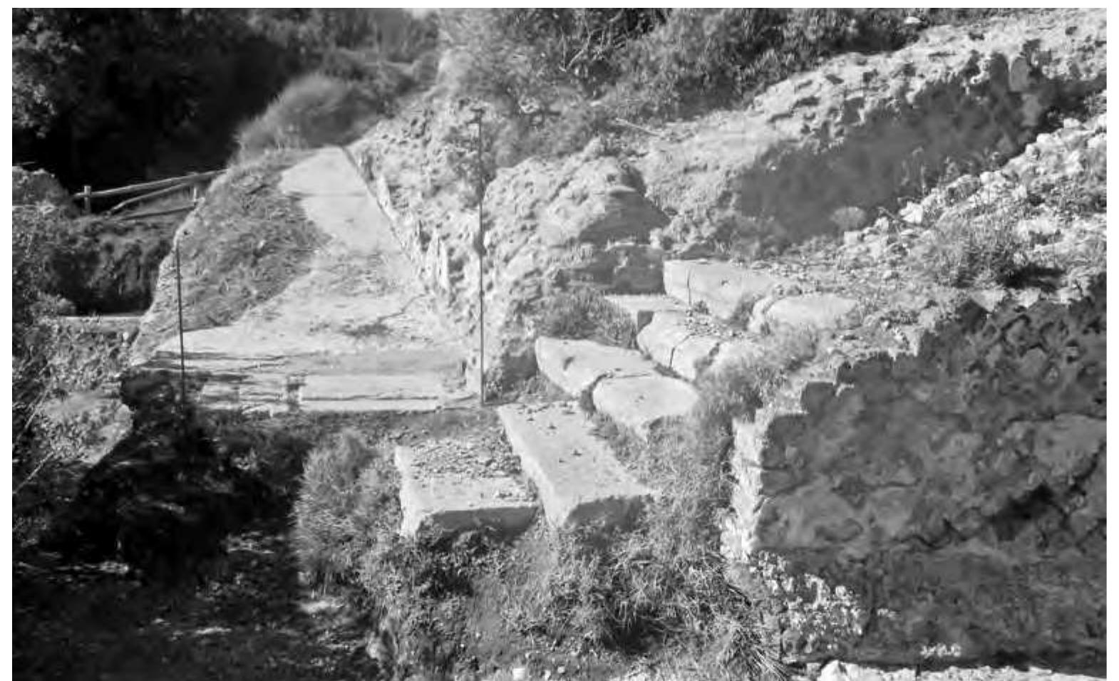 Fig. 10. The corner of the upper E ramp and adjoining staircase, both leading up to the quadriporticus. The opus reticulatum wall in the foreground is built in Sorrentine tuff, while the rest of the ramps consists of Neapolitar tuff. The division between ramps and stairs reflects the separation of élite persons borne on litters from servants who carried goods up the stairs (© W. Kennedy, Winckelmann-Institut, Humboldt-Universitat). 